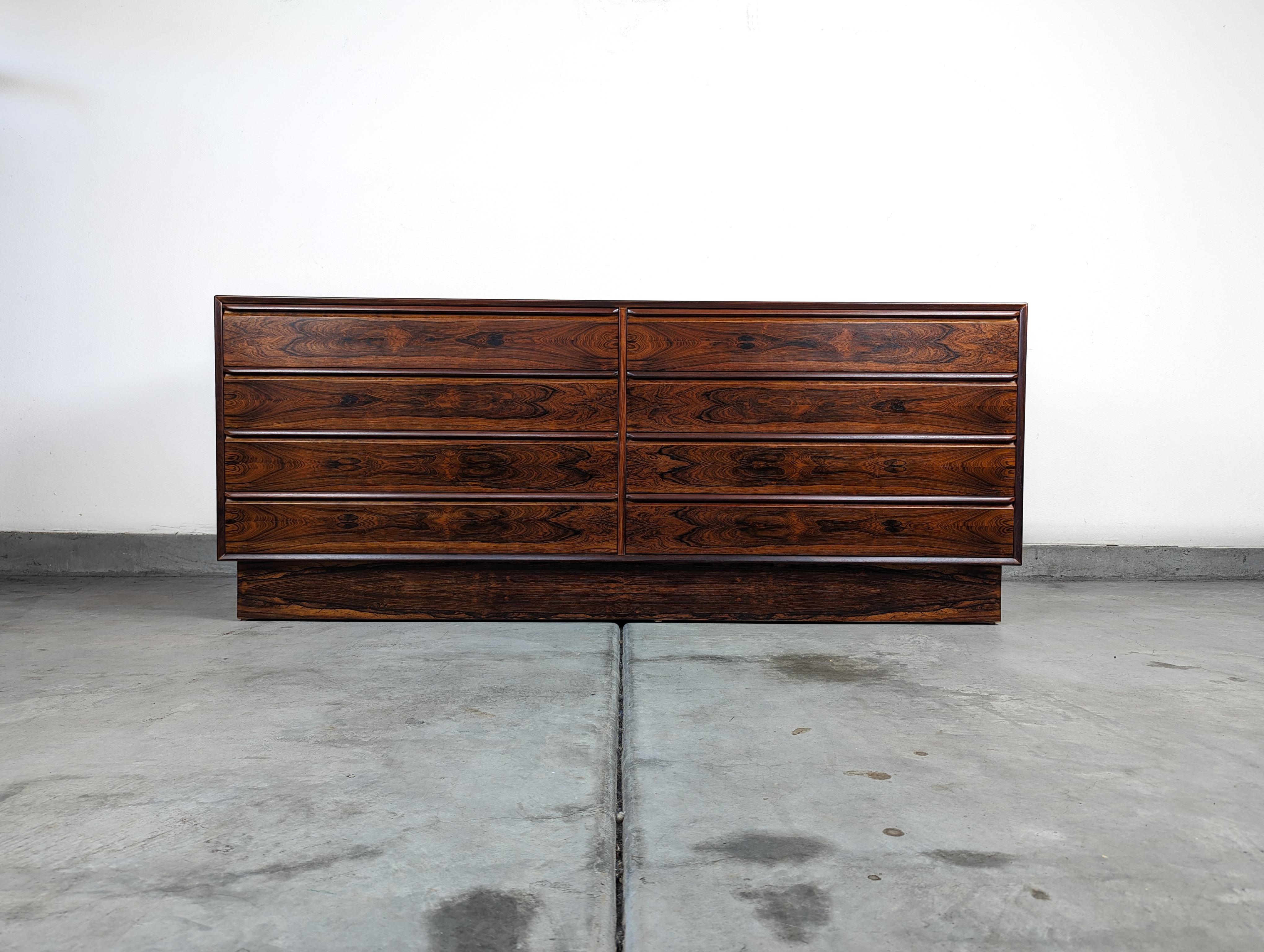 Step into a world of timeless elegance with this exquisite Mid Century 8-Drawer Lowboy Dresser by Westnofa, dating back to the captivating 1960s era. Masterfully crafted with an exotic Brazilian Rosewood finish, this dresser is not just a piece of