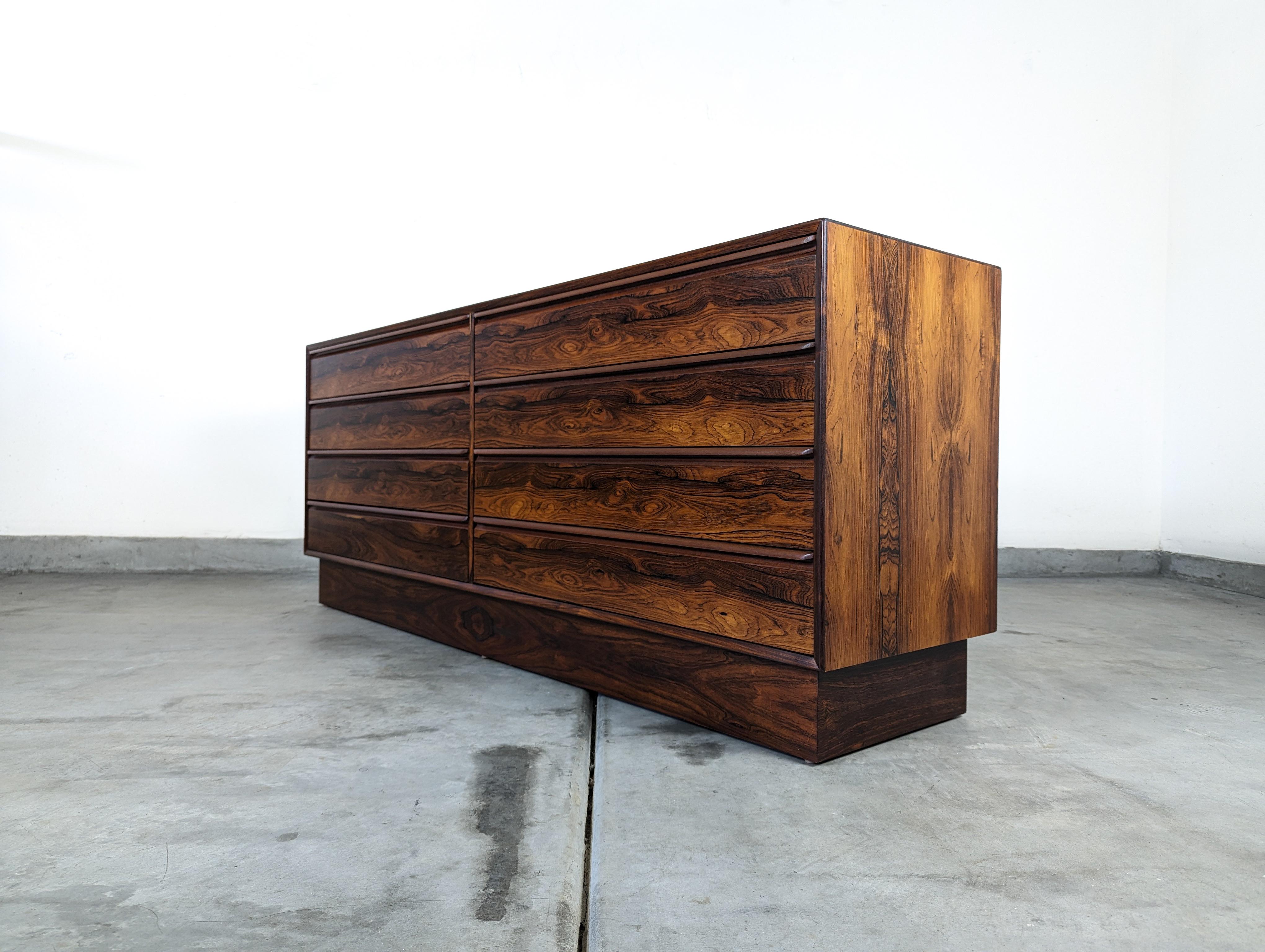 Step into a world of timeless elegance with this exquisite Mid Century 8-Drawer Lowboy Dresser by Westnofa, dating back to the captivating 1960s era. Masterfully crafted with an exotic Brazilian Rosewood finish, this dresser is not just a piece of