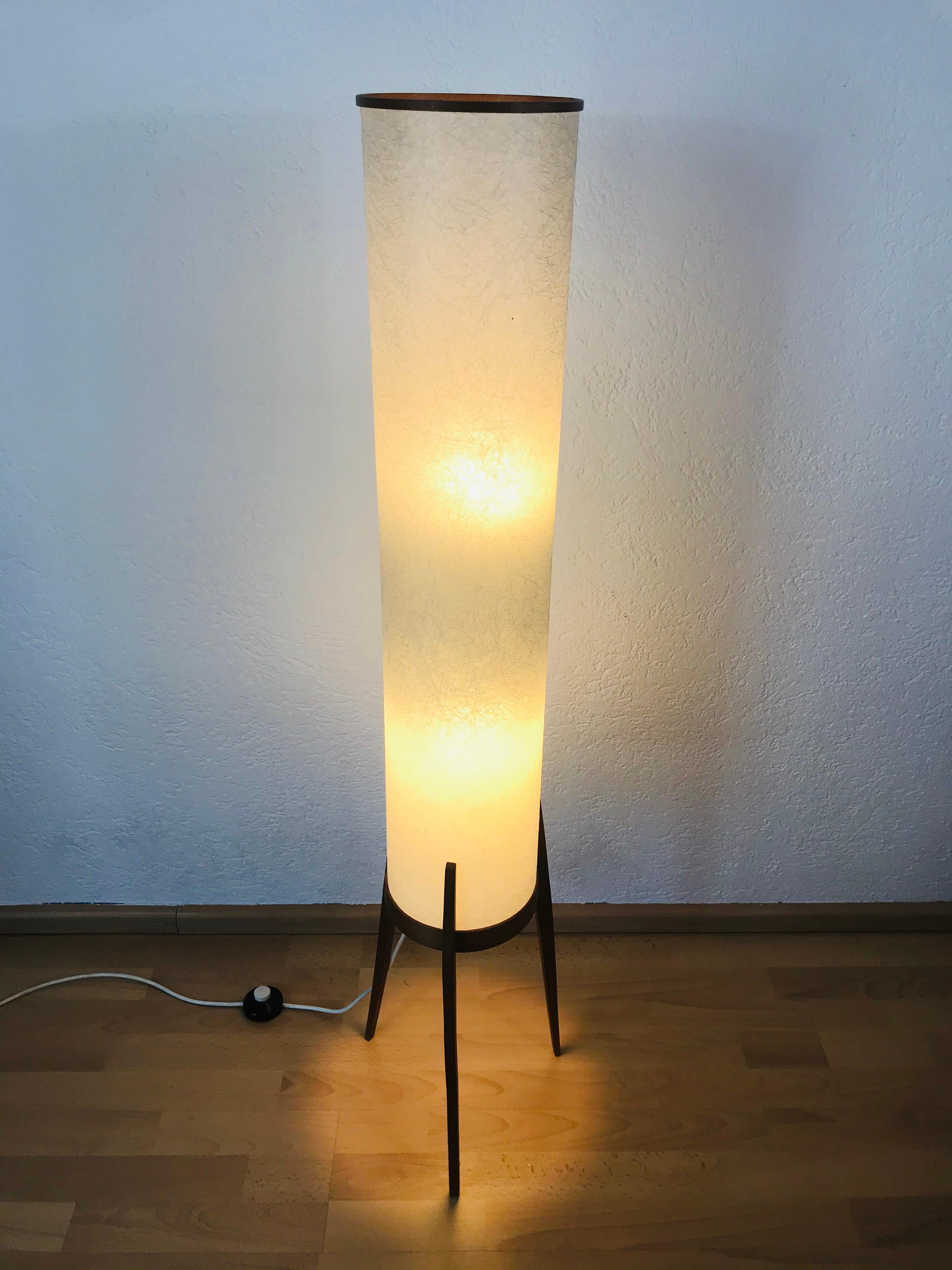 A midcentury floor lamp made in the 1960s. It is fascinating with its midcentury design and shade. The bottom of the light is teak wood. There are two E27 sockets in the body.

Very good vintage condition. The lighting requires two E27 light