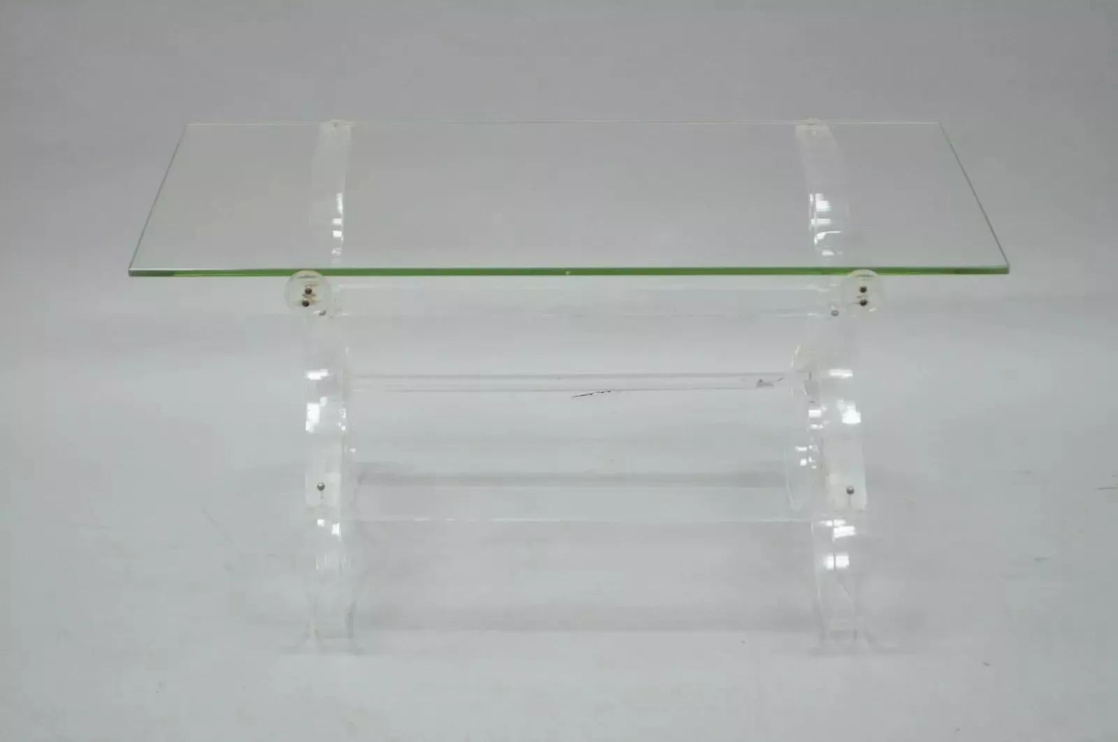 Table basse Vintage Mid Century Modern en Lucite et Verre Hollywood Regency. Cet objet se caractérise par une base en lucite à volutes, un plateau en verre transparent encastré, un design épuré, un bel objet vintage. Circa Mid 20th Century.