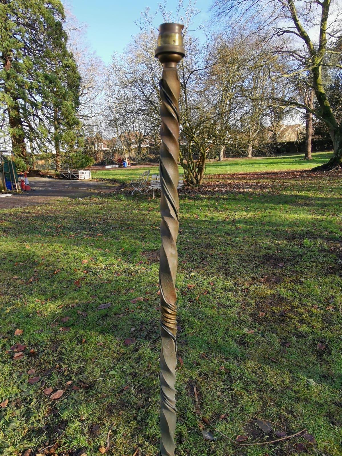 Élégant lampadaire en fer forgé de style français du milieu du siècle dernier, orné de volutes décoratives, avec une table circulaire en verre au centre, sur des pieds évasés.