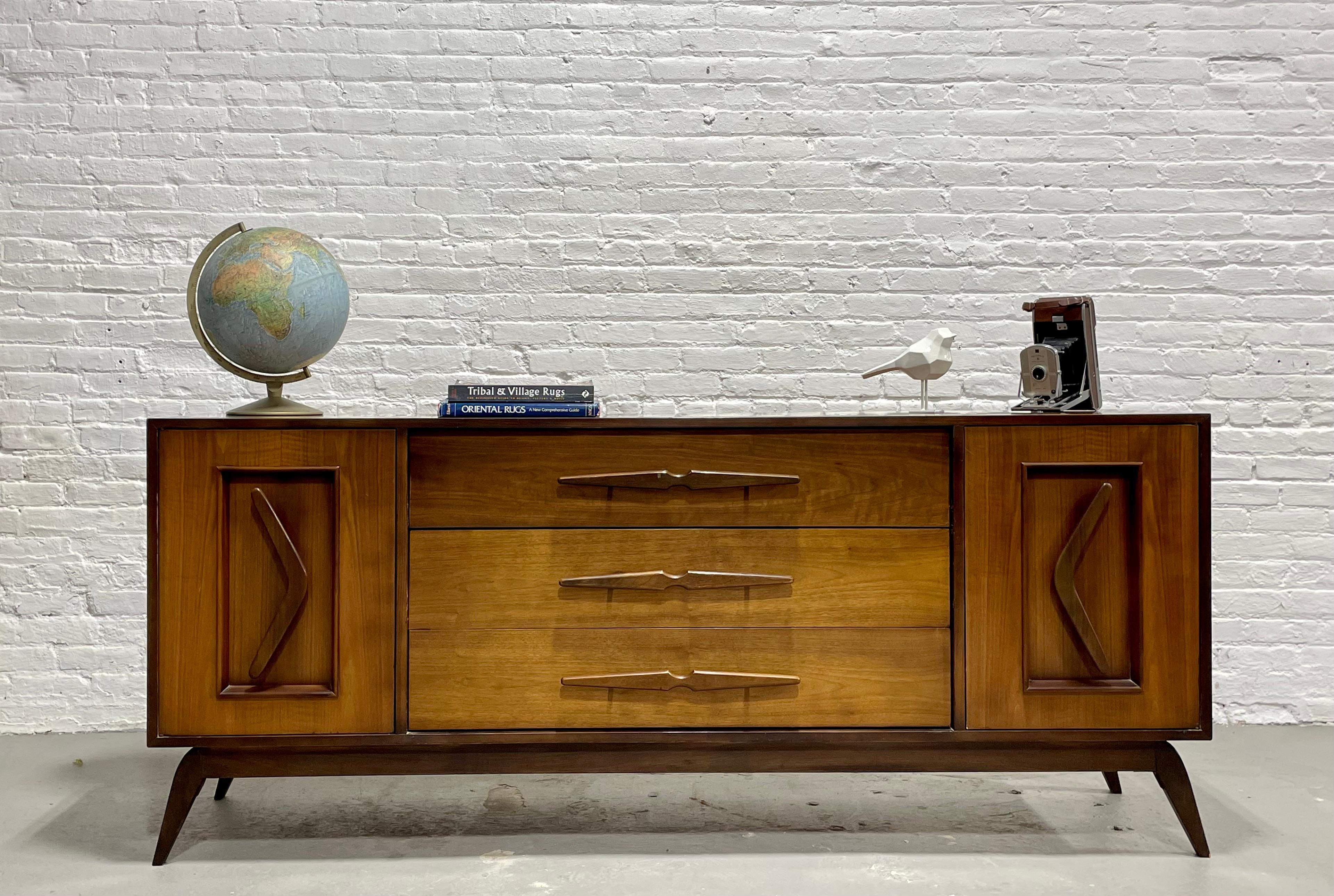 Mid-Century Modern Bedroom Set - Long Dresser / Sideboard + Nightstands, circa 1960s.

Mid-Century Modern Long Dresser / Sideboard with boomerang hand-pulls along the side cabinet doors, sculpted center pulls and splayed legs along the solid base.