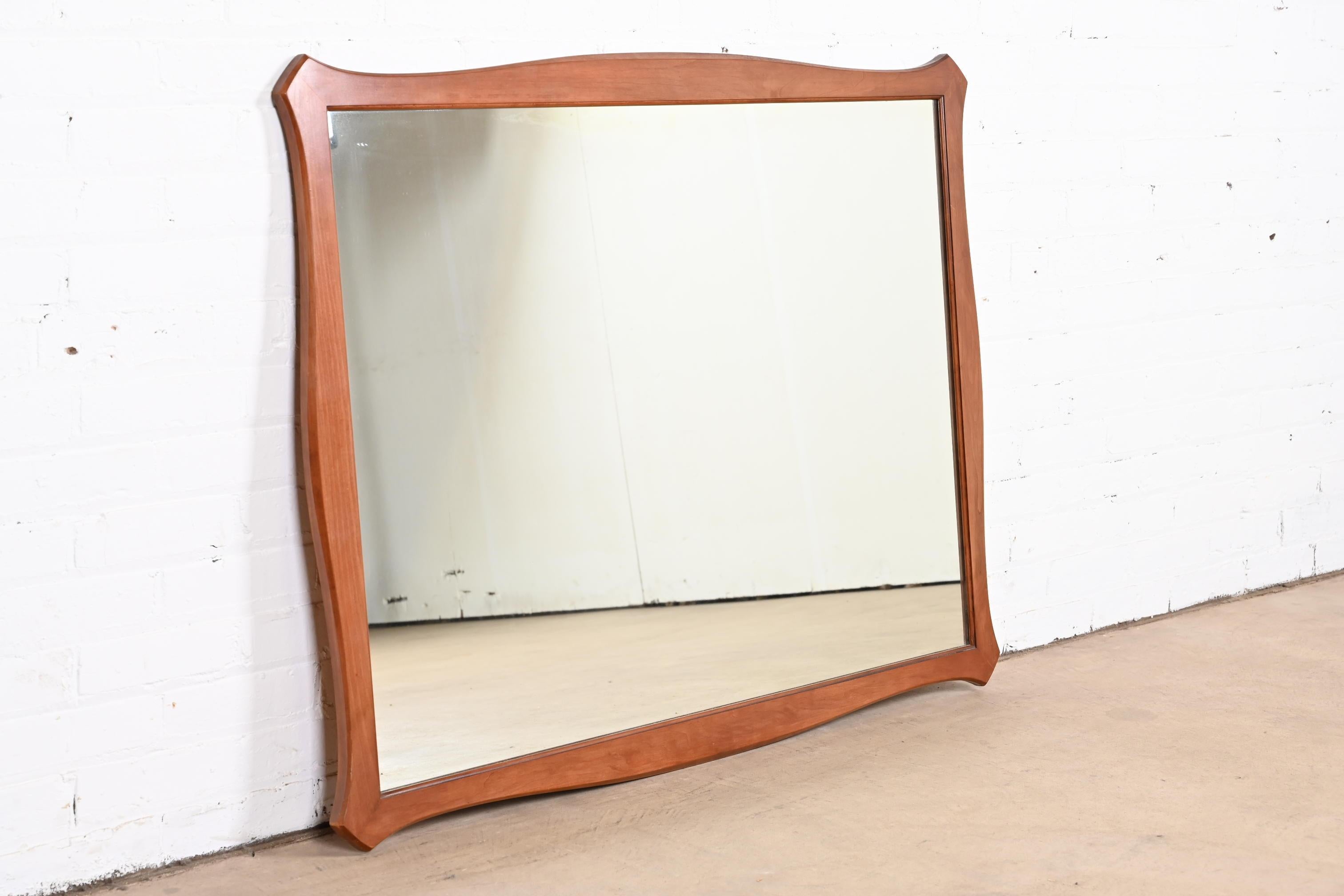 A stylish Mid-Century Modern sculpted cherry wood framed wall mirror

USA, 1960s

Measures: 46.25