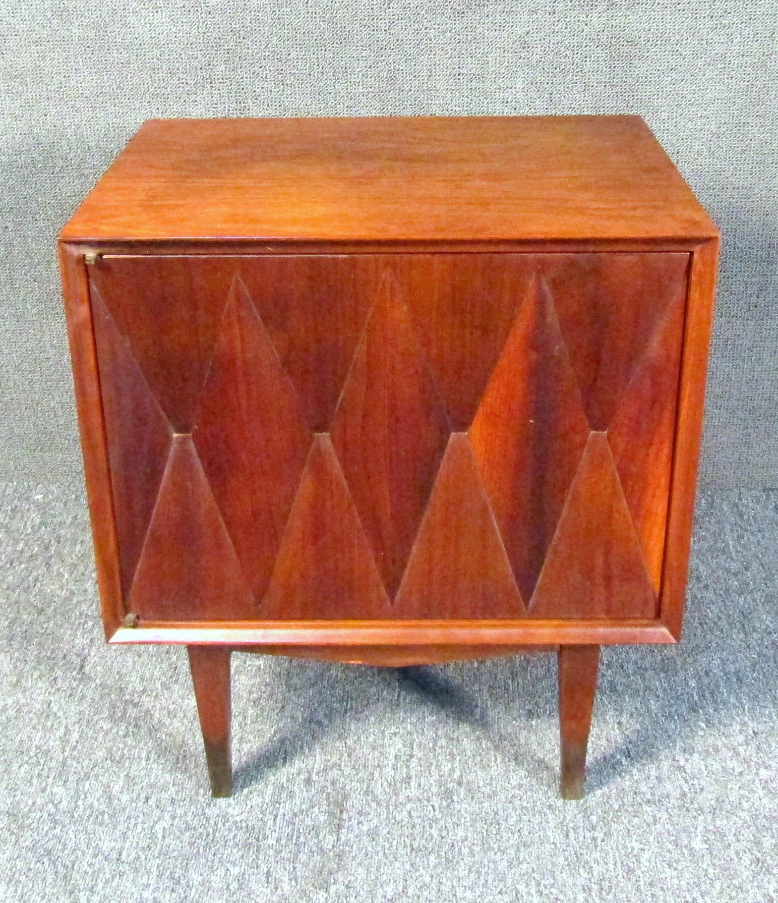 This vintage modern sculpted front nightstand features a diamond front cabinet door concealing shelved storage space. This unique Mid-Century storage table makes a great living room end table or bedside nightstand. Please confirm item location (NY
