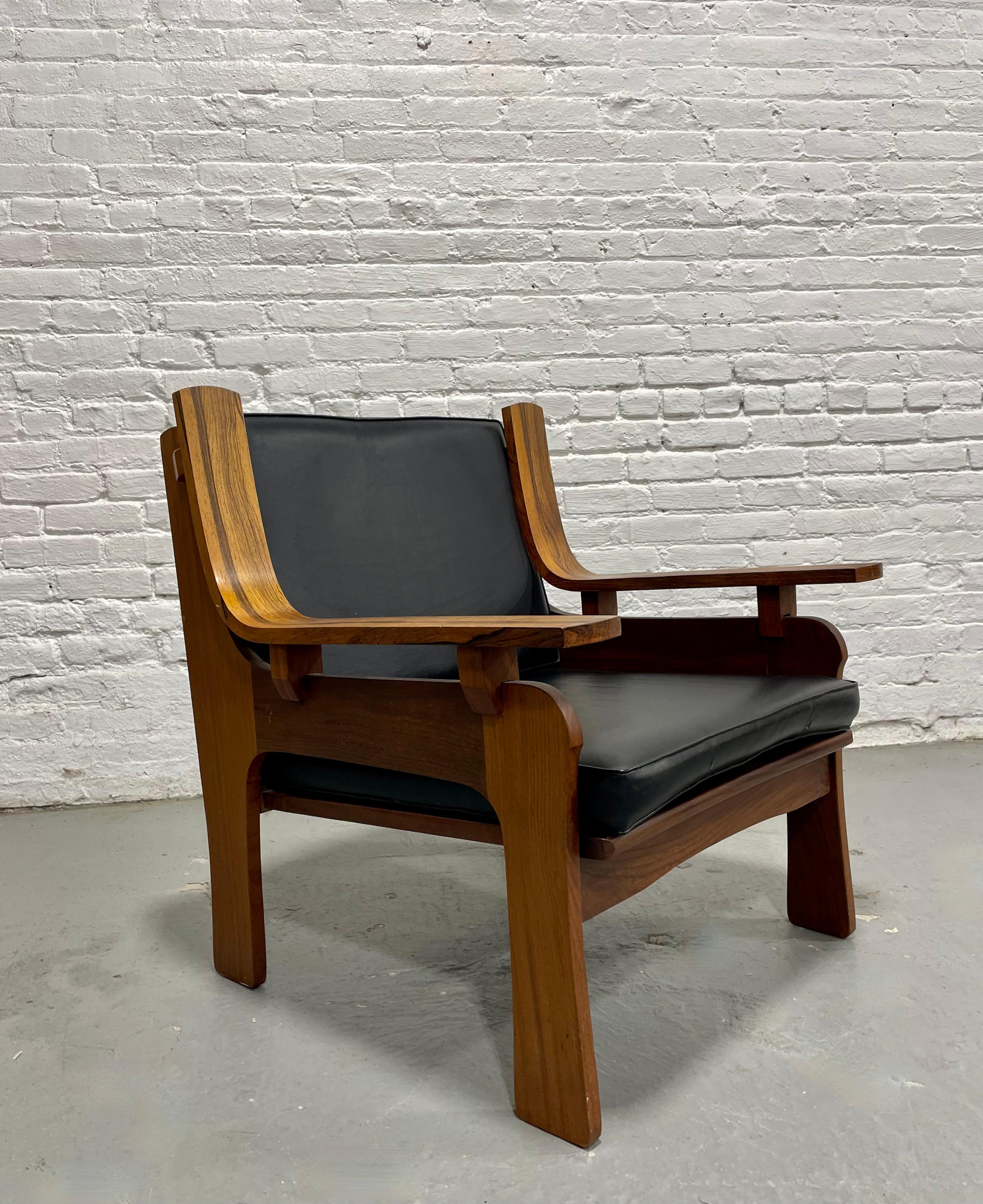 Chaise de salon sculptée de style moderne du milieu du siècle, avec une construction en noyer et en bois de rose magnifiquement grainé et des coussins élégants en vinyle noir. Le cadre architectural présente des accoudoirs audacieux et incurvés qui