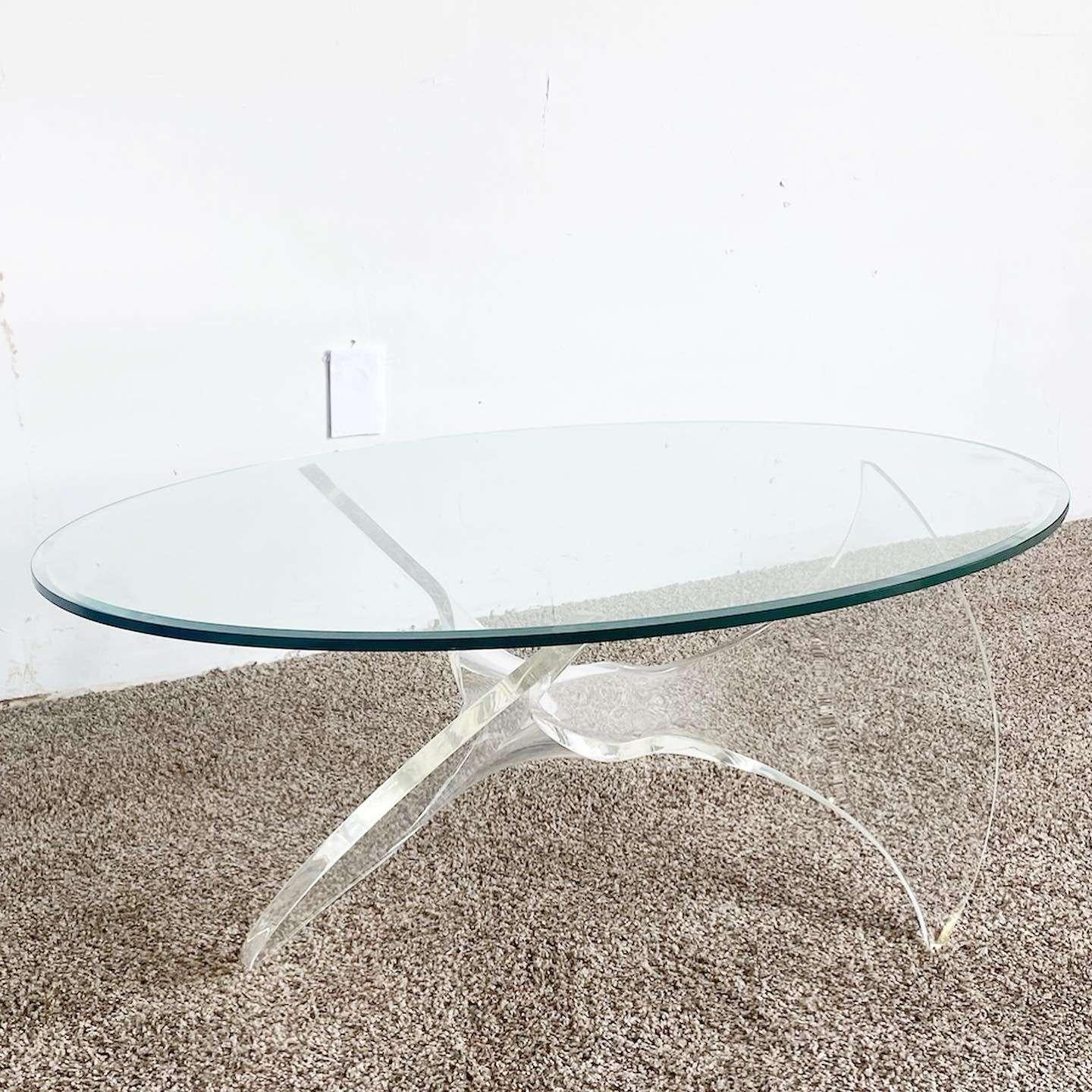 Incredible vintage mid century modern oval glass top lucite coffee table. The vase of this table displays a fantastic sculpted shape which holds up the glass on the three prongs.