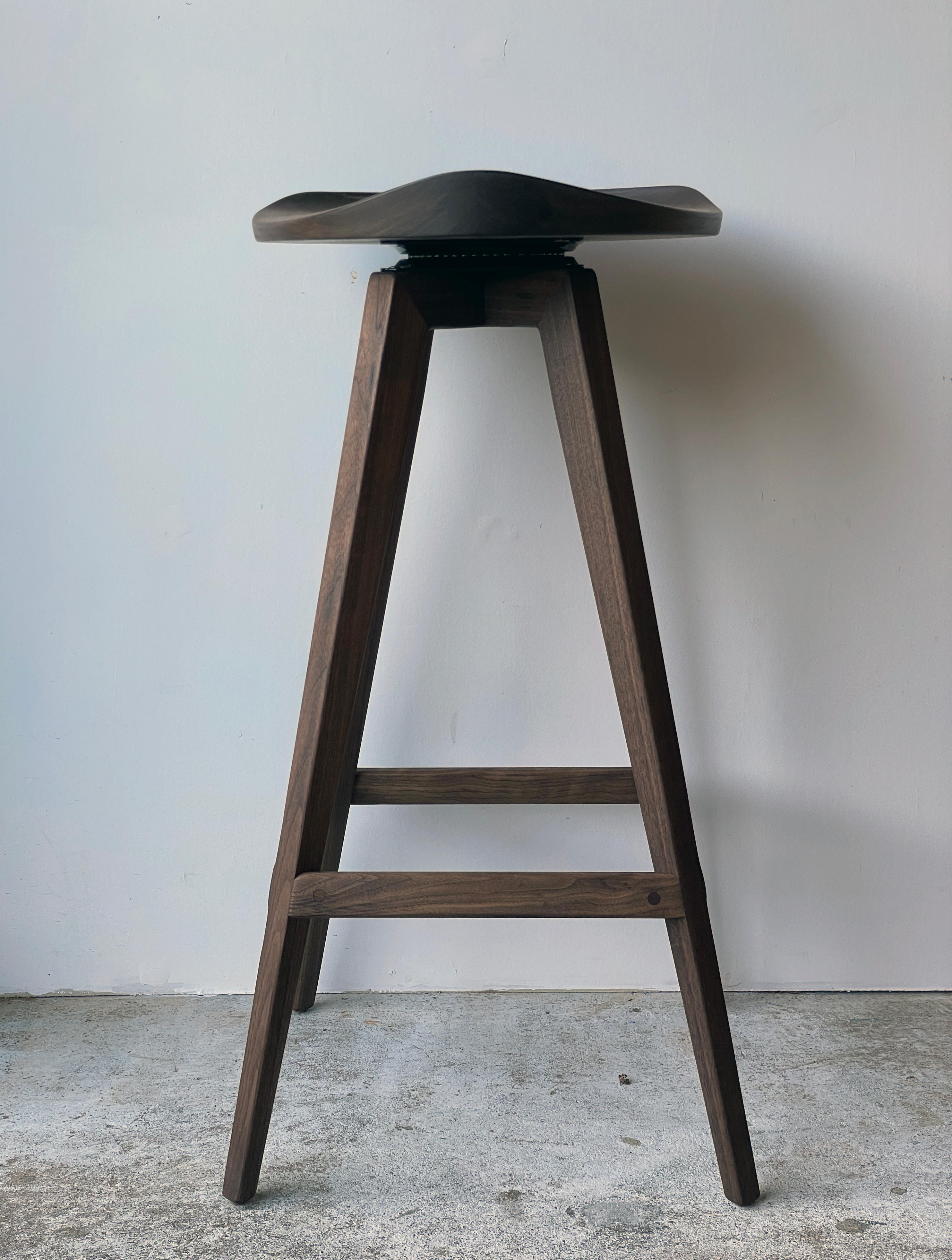 Tabouret pivotant de style Mid-Century Modern avec dossier à profil bas sculpté à la main et assise de type tracteur. 

Le cadre est construit par tenons et mortaises. L'assise et le dossier sont formés en sélectionnant soigneusement des blocs de