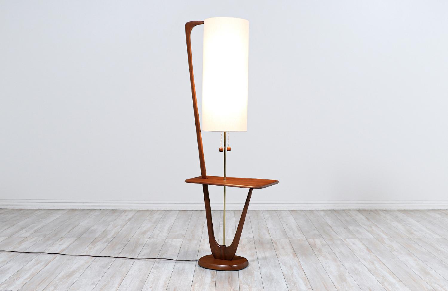 Vintage modern floor lamp designed and manufactured in the United States in the 1960s. Our stylish Mid-Century Modern lamp features a sculpted and solid walnut wood frame with organic shapes for a stunning grain detail throughout, adding a warm