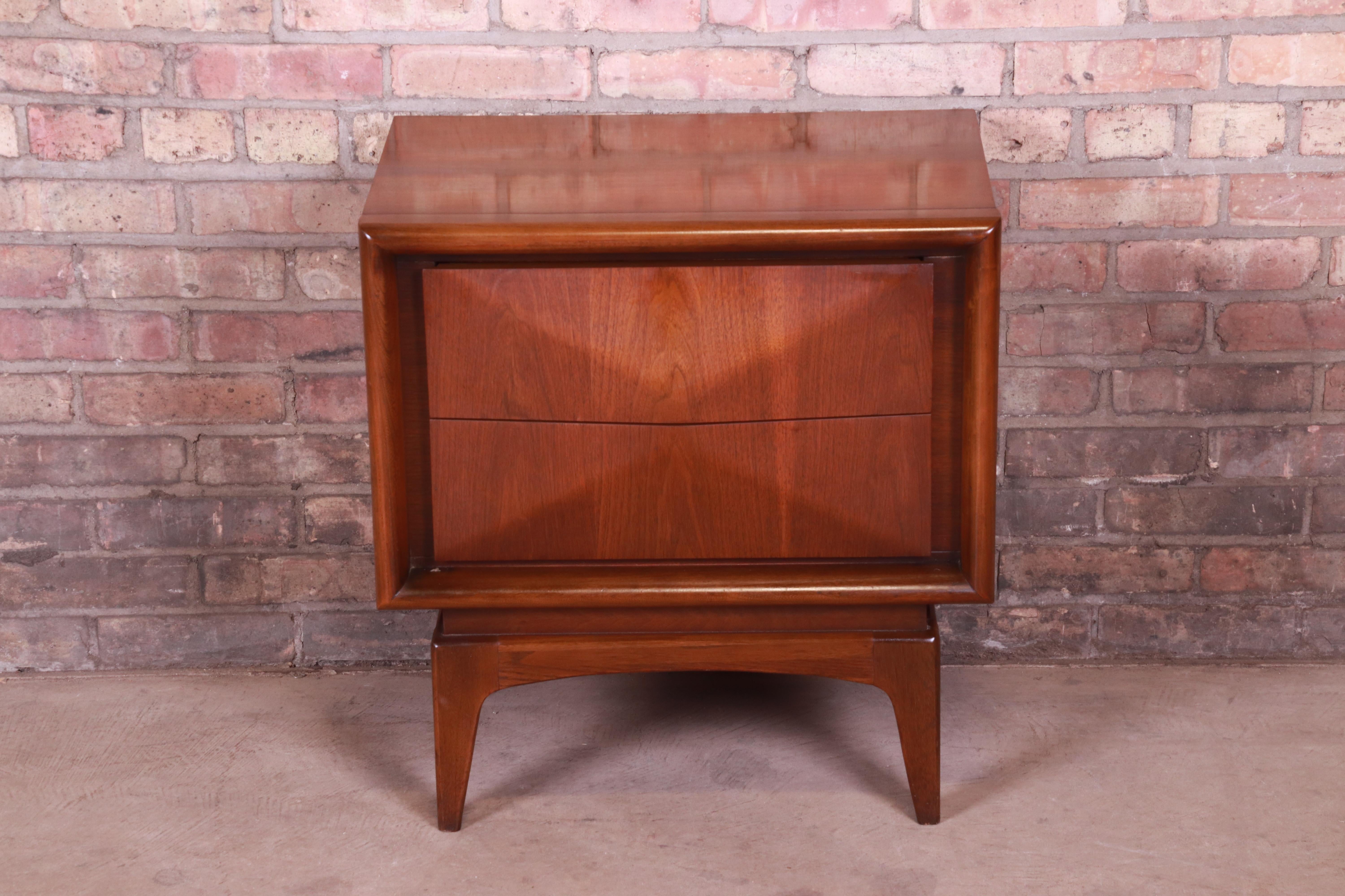A stunning Mid-Century Modern sculpted walnut diamond front nightstand.

In the manner of Vladimir Kagan

By United Furniture Co.

USA, 1960s

Measures: 23