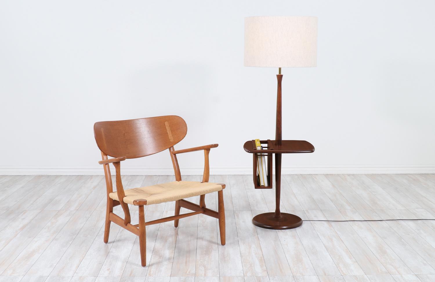 Floor Lamp manufactured by Laurel Lamp Co. in the United States circa 1960’s. This beautiful Mid-Century Modern lamp features a tall walnut wood body that supports a table with a removable magazine rack. The lamp is professionally refinished and