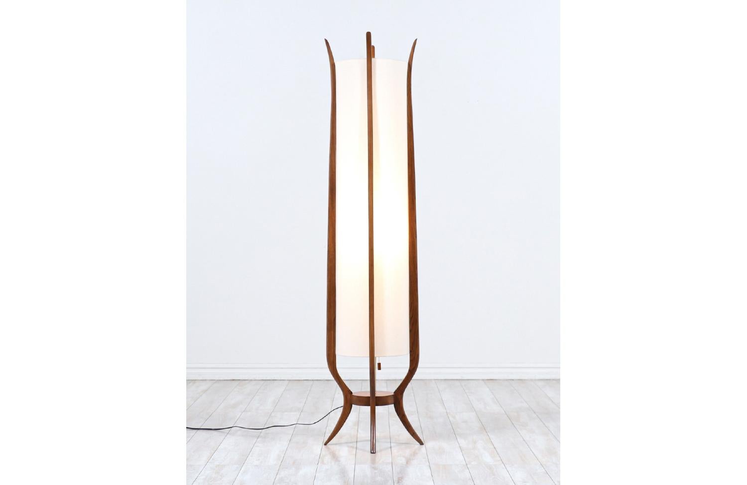 Dazzling sculpted walnut floor lamp designed and manufactured in the United States circa 1960s. This sculpted Mid-Century lamp features a carved walnut wood frame composed of four curved columns that hold the new linen shade vertically. This piece