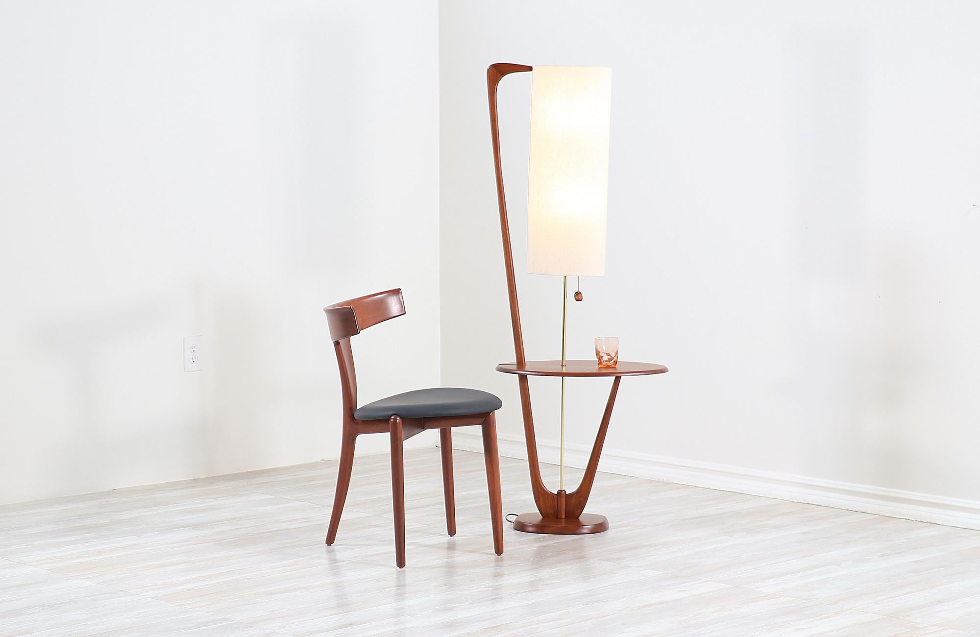 Vintage modern floor lamp designed and manufactured in the United States, circa 1960s. This stylish Mid-Century Modern lamp features a tall and solid walnut wood frame with organic shapes and a stunning grain detail throughout adding a warm flair to