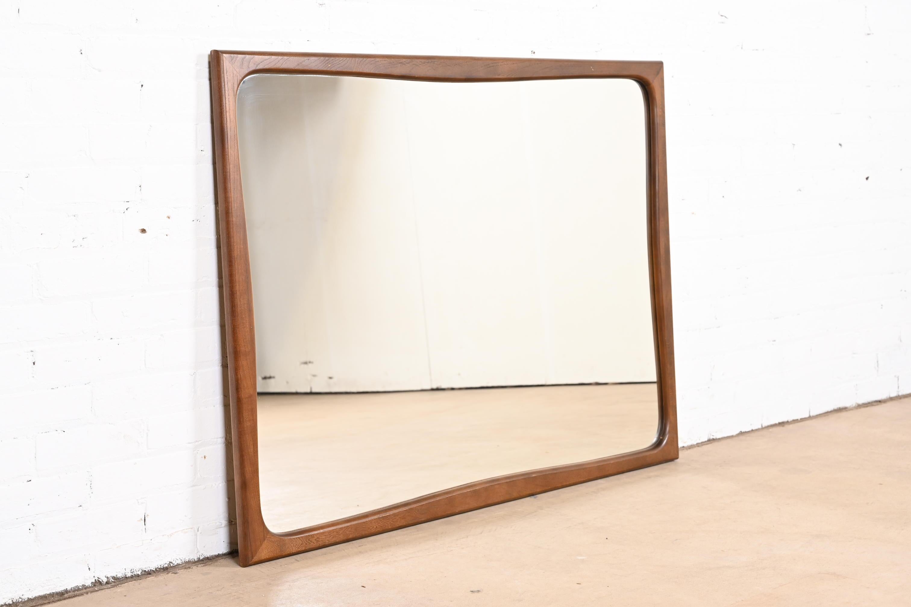 A stylish Mid-Century Modern sculpted walnut framed wall mirror

USA, 1960s

Measures: 48