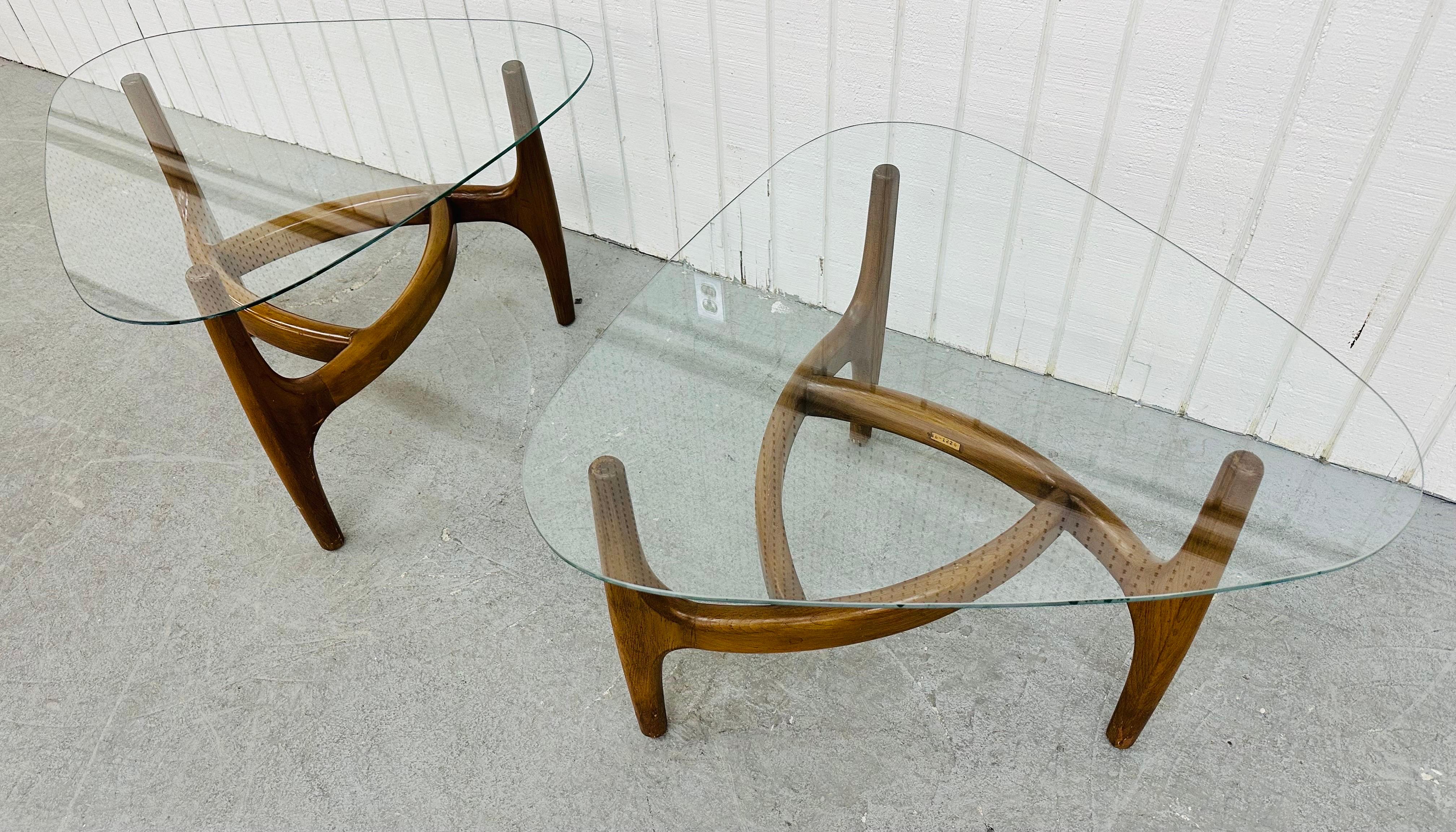 This listing is for a pair of Mid-Century Modern Sculpted Walnut Glass Top Side Tables. Featuring a sculpted curved wooden base, rounded triangular glass tops, and a beautiful walnut finish. This is an exceptional combination of quality and design