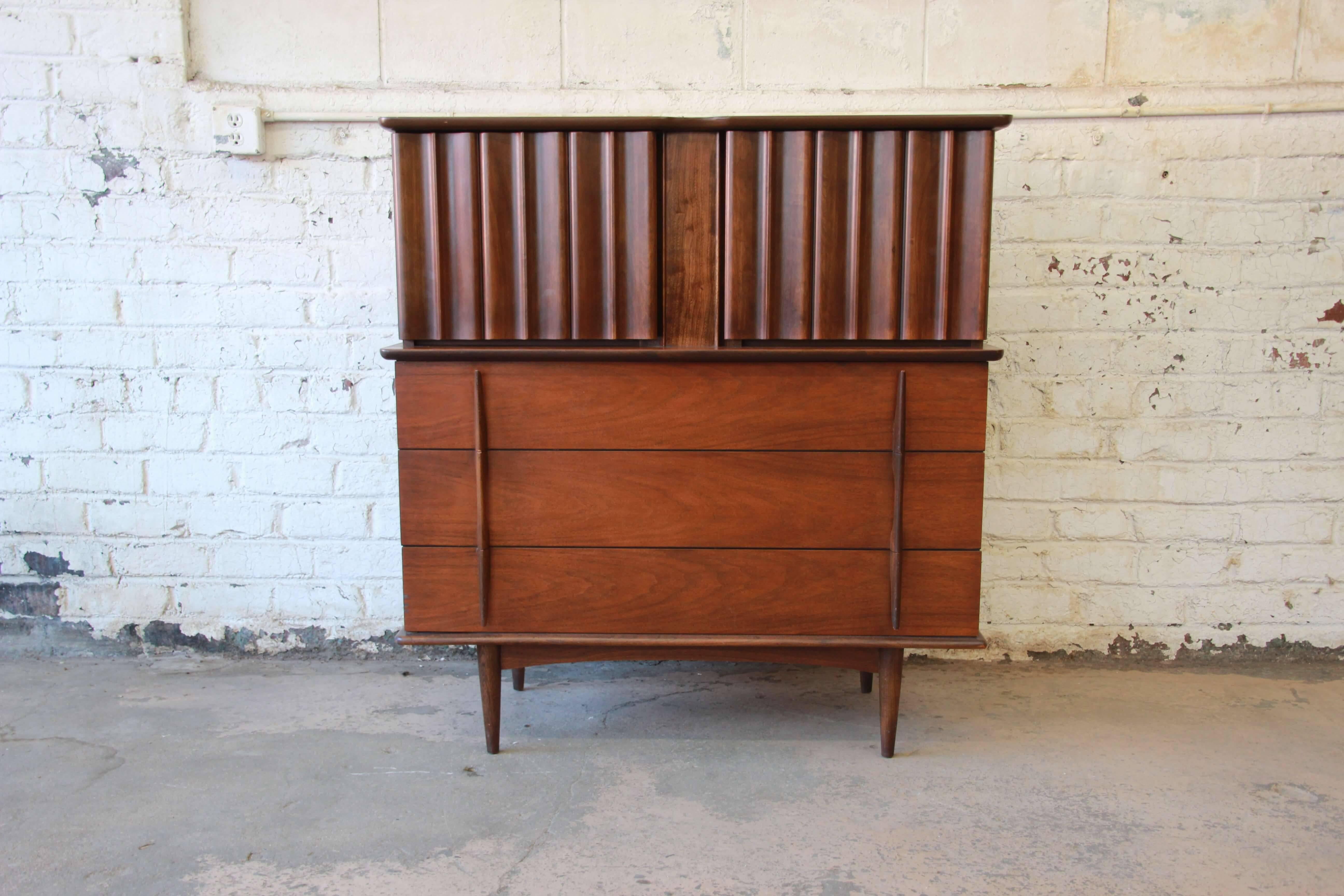 Offering a very nice sculpted walnut highboy dresser by United Furniture Co. The dresser has unique sculpted pulls on the bottom three drawers that open and close smoothly. Above are two cabinet doors that open to reveal four additional drawers for