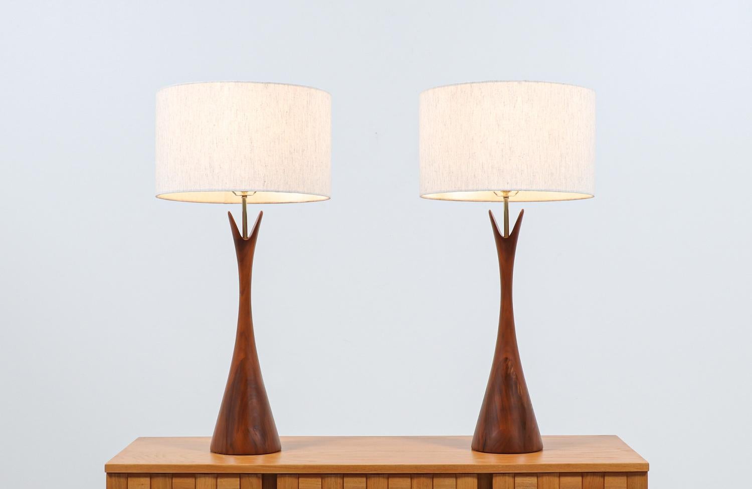 Mid-Century Modern walnut table lamps manufactured by Modernera Lamp Co. in the United States in the 1950’s. The sculpted walnut bodies resemble the shape of an hourglass with two prongs on top creating a mixture of artistic shape and is