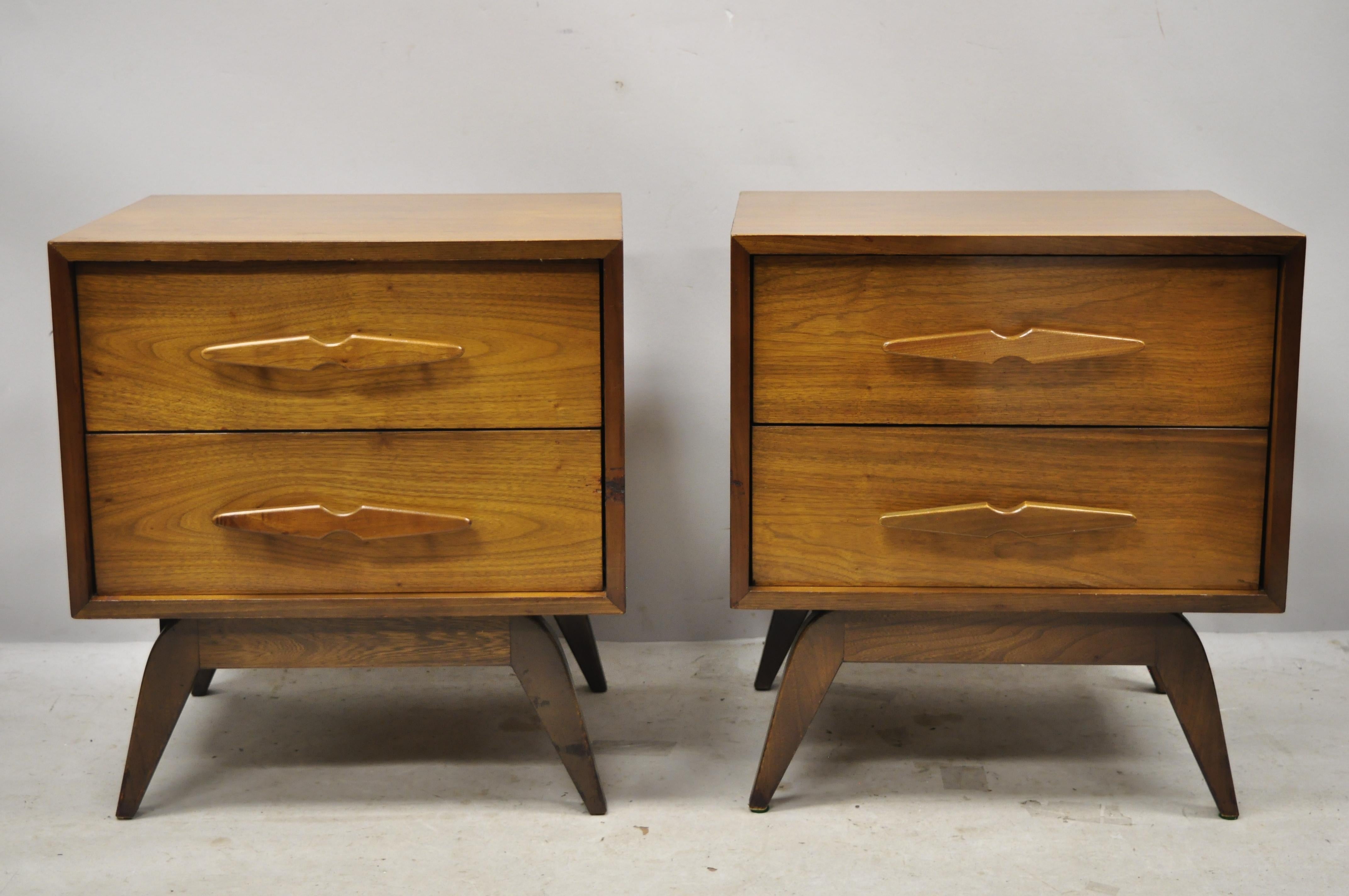 Vintage Mid-Century Modern sculpted walnut two-drawer nightstands bedside tables - a pair. Item features carved wood pulls, brass accents, beautiful wood grain, tapered legs, clean modernist lines, great style and form, circa mid-20th century.