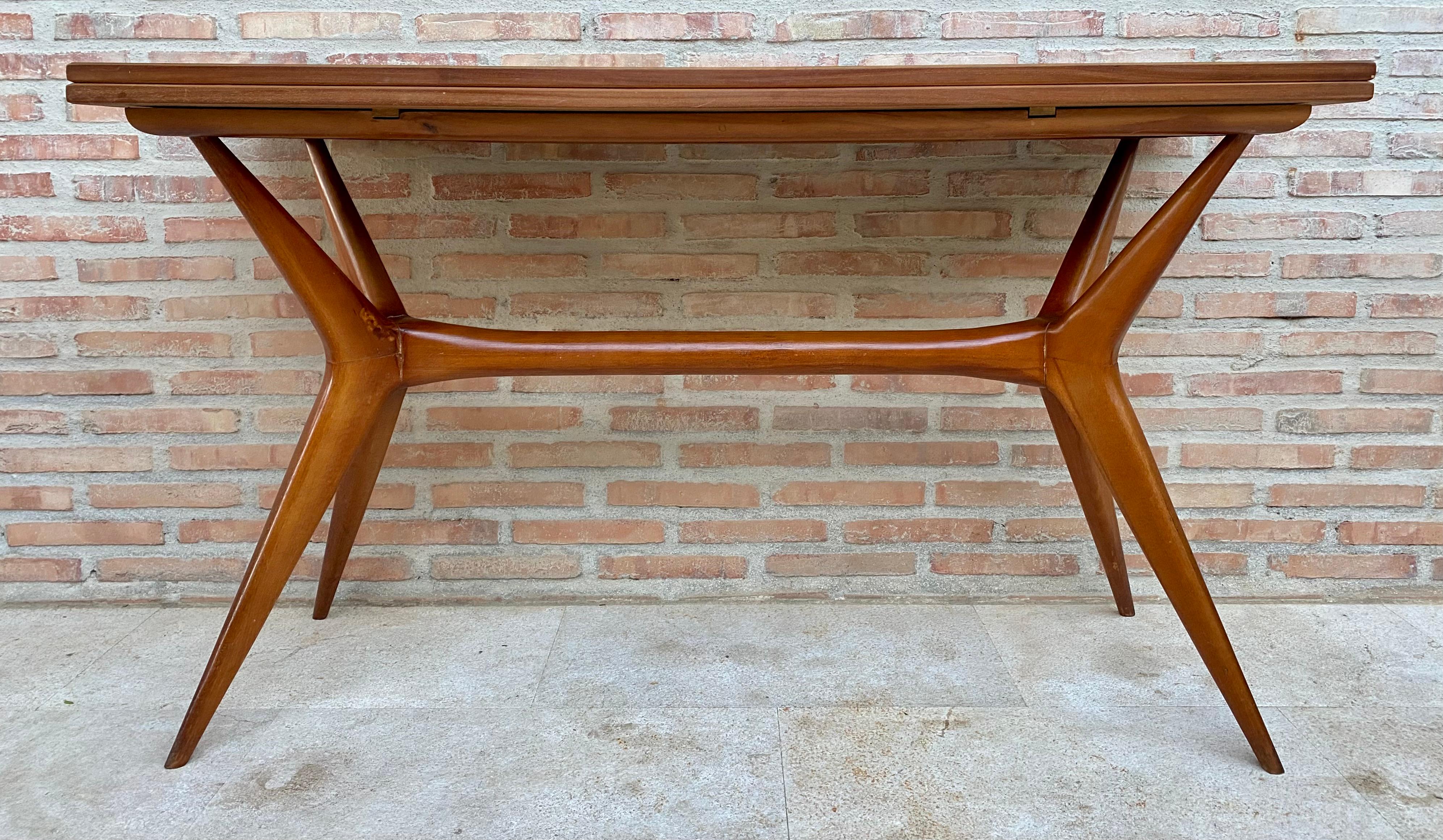 This beautiful sculptured base dining table features exquisite details including tapered X-shaped legs and a beautiful wood top that retains its original finish in excellent shape. We love the way mid-century Italian designers used both lacquered