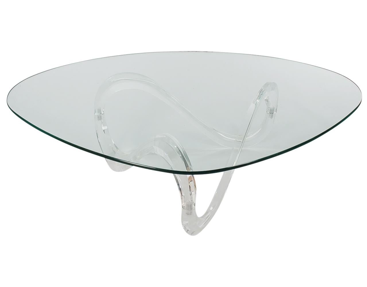 An incredible conversation piece designed by Knut Hesterberg. This model was manufactured in the 1970s. It features a thick continuous Lucite form base with a rounded edge triangular shaped glass top.