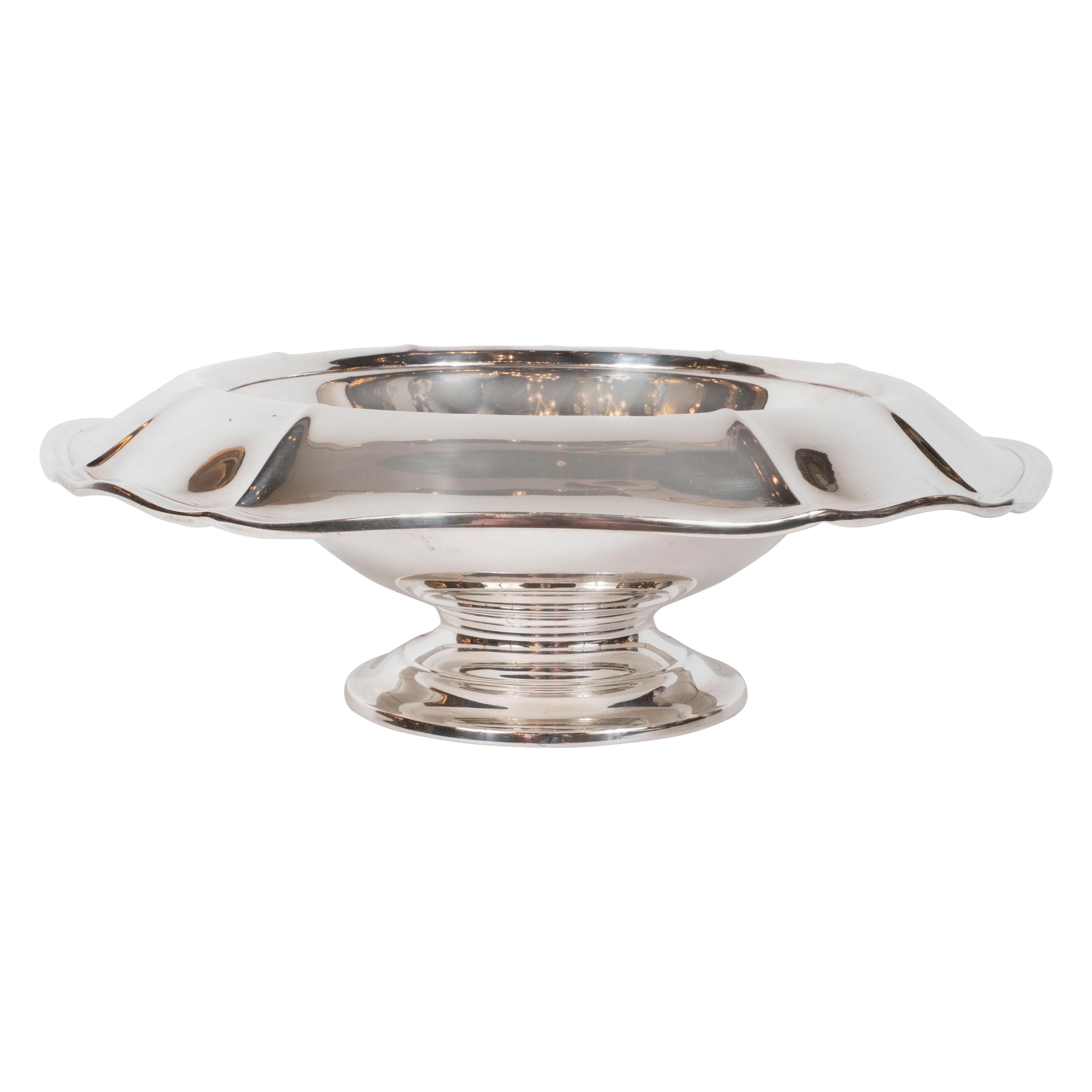This elegant Mid-Century Modern centerpiece bowl was realized in the United States, circa 1950. It features undulating sides; a stepped base and a recessed center all realized in lustrous sterling silver. With its sculptural profile and clean