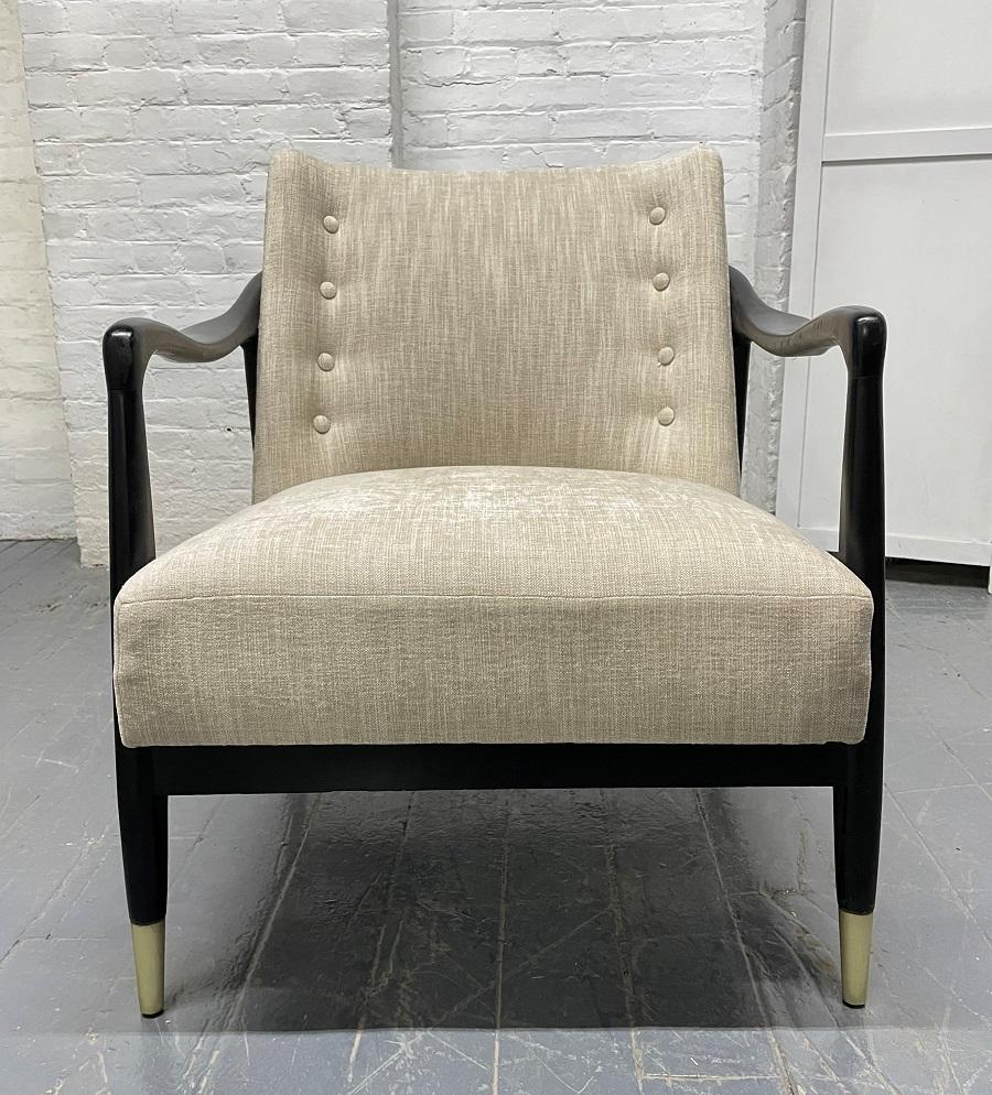 Mid-Century Modern sculptural armchair. The chair has a black lacquered wood sculptural frame, upholstered and has brass feet. Style of Gio Ponti.