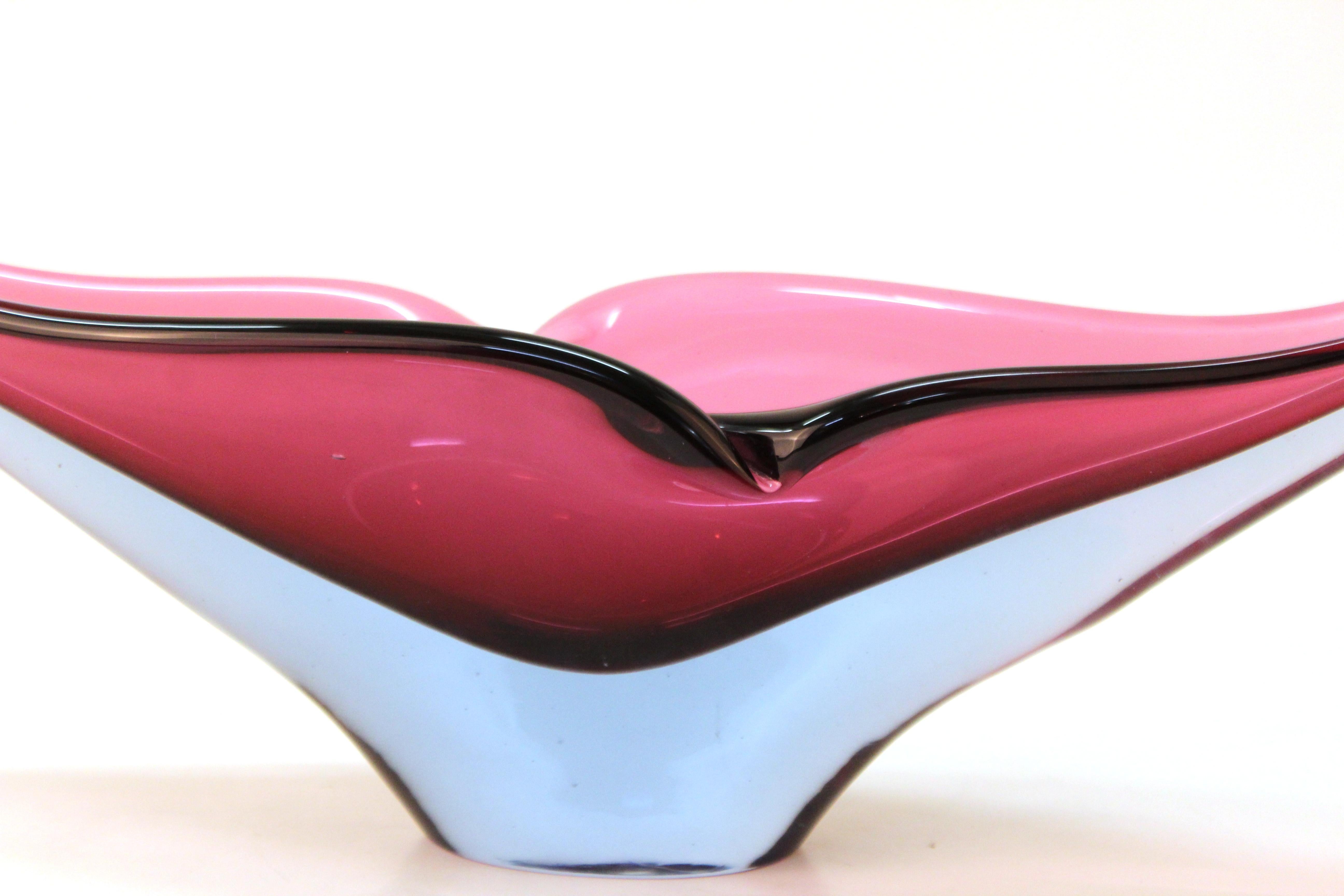 Mid-Century Modern sculptural art glass bowl in eggplant purple encased in clear glass. The shape of this decorative bowl is reminiscent of a bird taking flight. Some minor contact scratches on the bottom, but in overall great vintage condition.