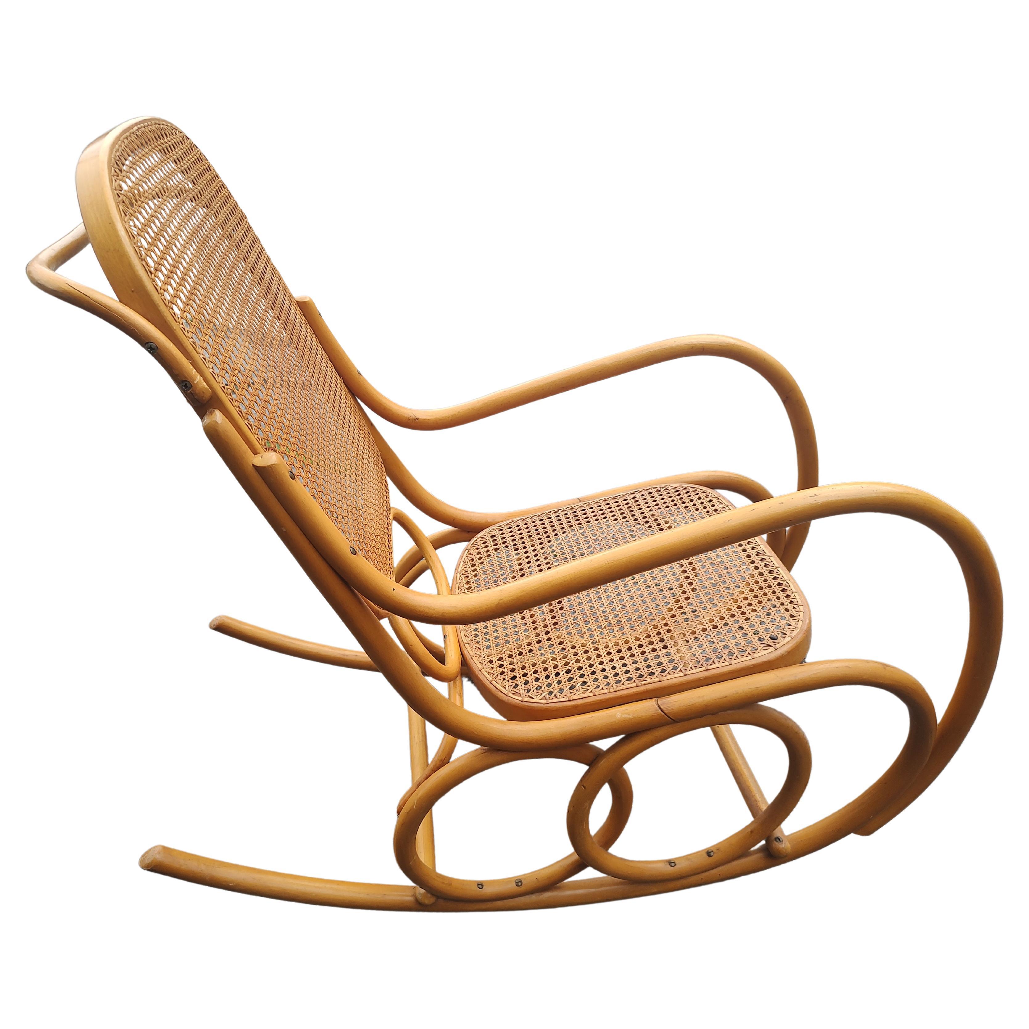 Simple et élégante chaise à bascule Thonet en bois courbé sculpté, originaire de Tchécoslovaquie, vers 1960. Assise et dossier cannés à la main avec un fabuleux design en bois courbé. Des cercles concentriques forment la base avec d'autres éléments