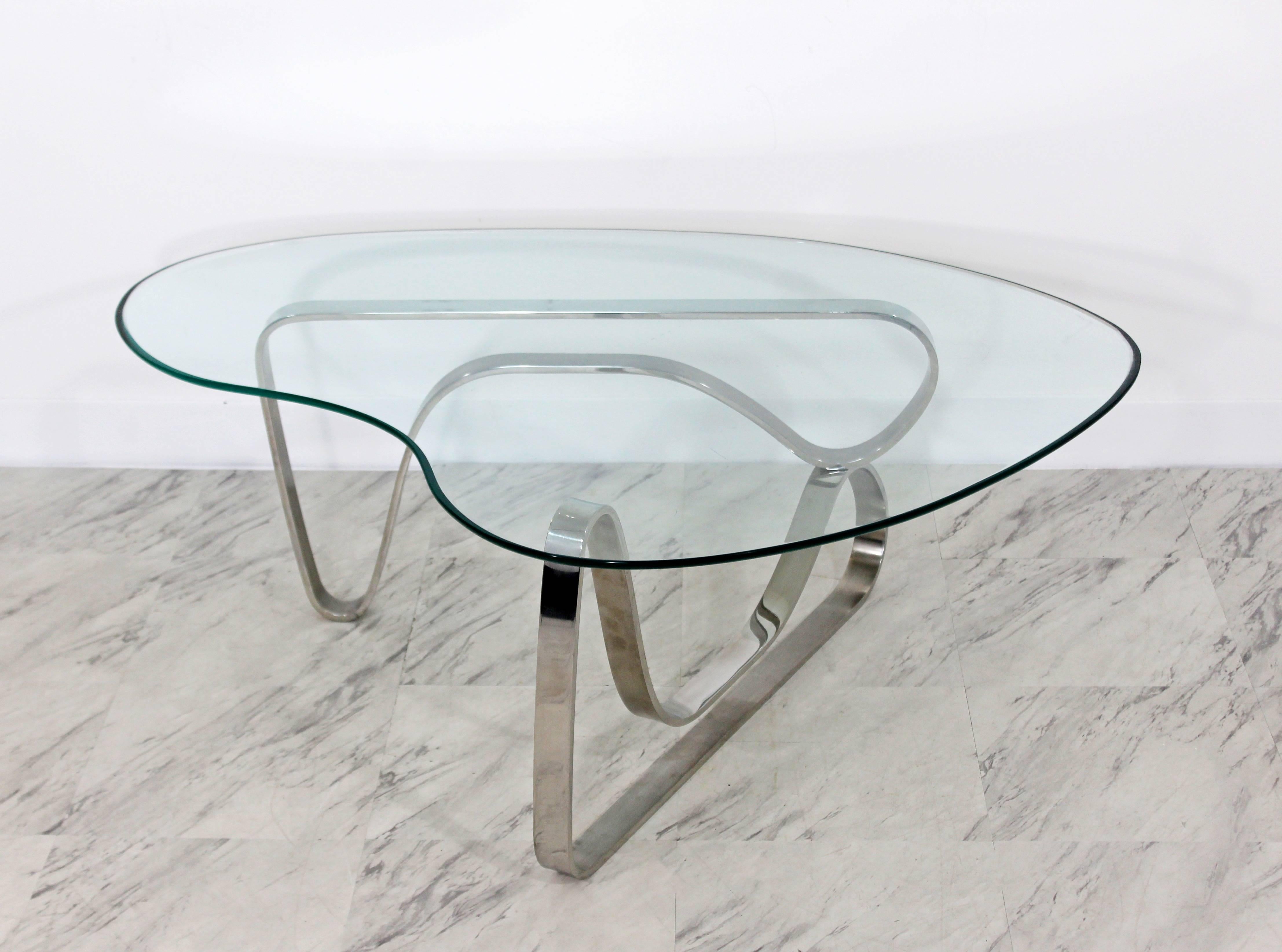 For your consideration is a unique and luxe looking coffee table, with a sculptural asymmetrical chrome base and kidney shaped glass top, Pace attributed, circa the 1970s. In excellent condition, with a light patina to match its age. The dimensions