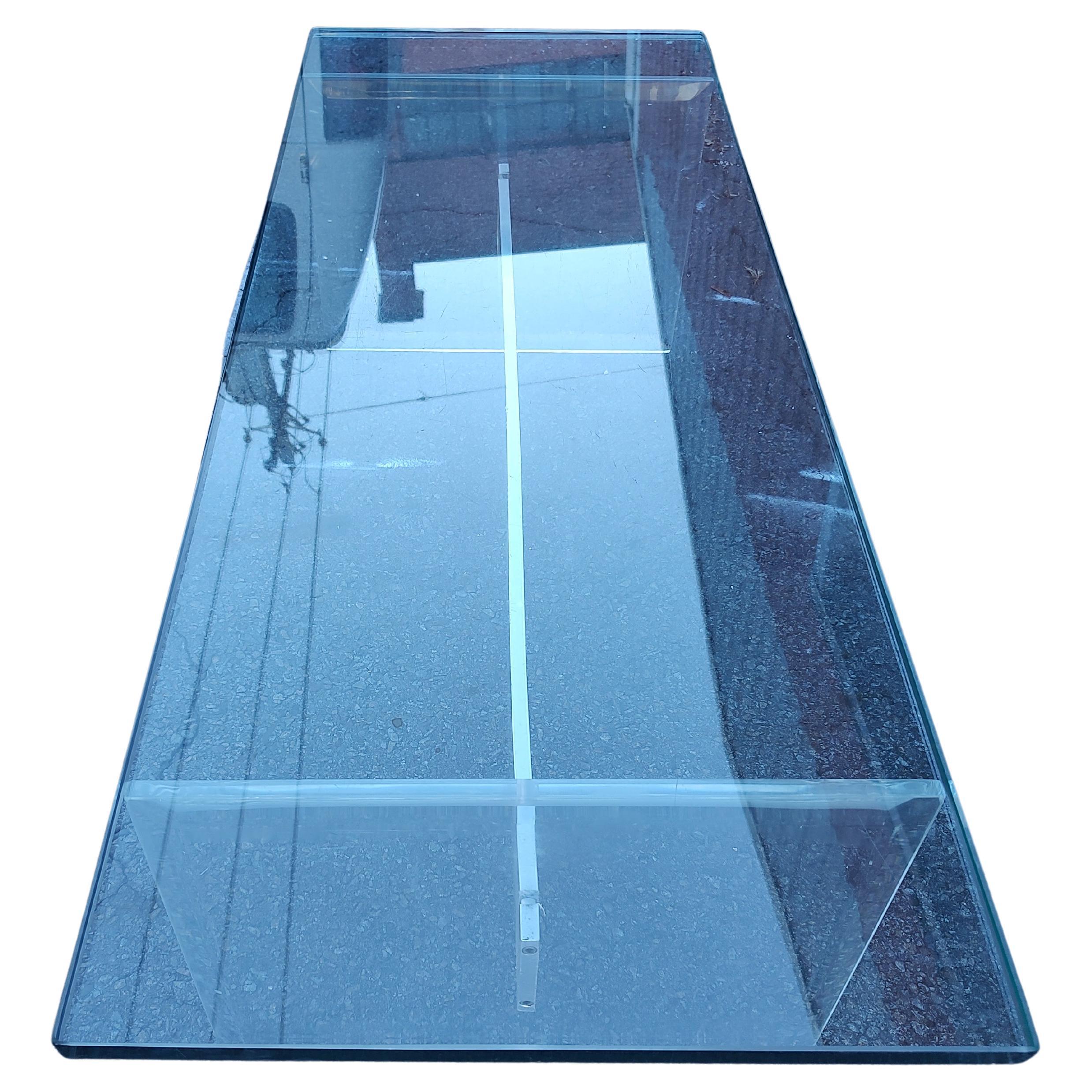 Fabulosa mesa de cóctel de estilo sencillo con una tapa de cristal grueso dimensional apoyada en soportes de losa de lucita biselada y un tirante de aluminio centrado. Todo en excelente estado vintage con un desgaste mínimo, algunos roces en el