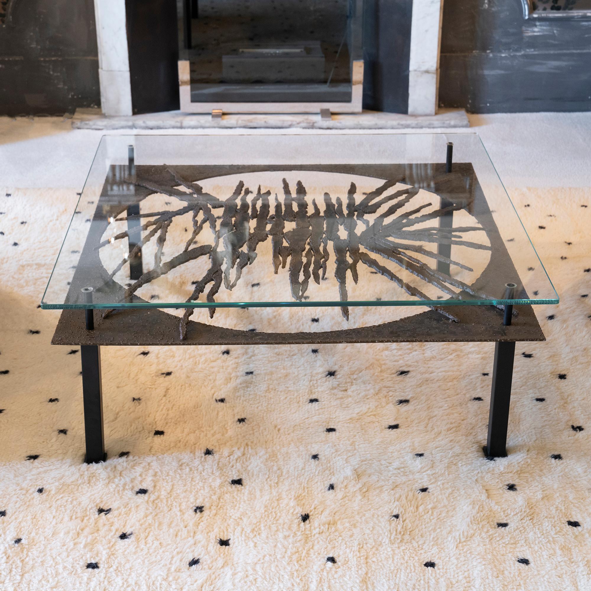 Sculptural coffee table black steel base with decorative forged iron round frieze, clear glass top, Italy 1960s circa.