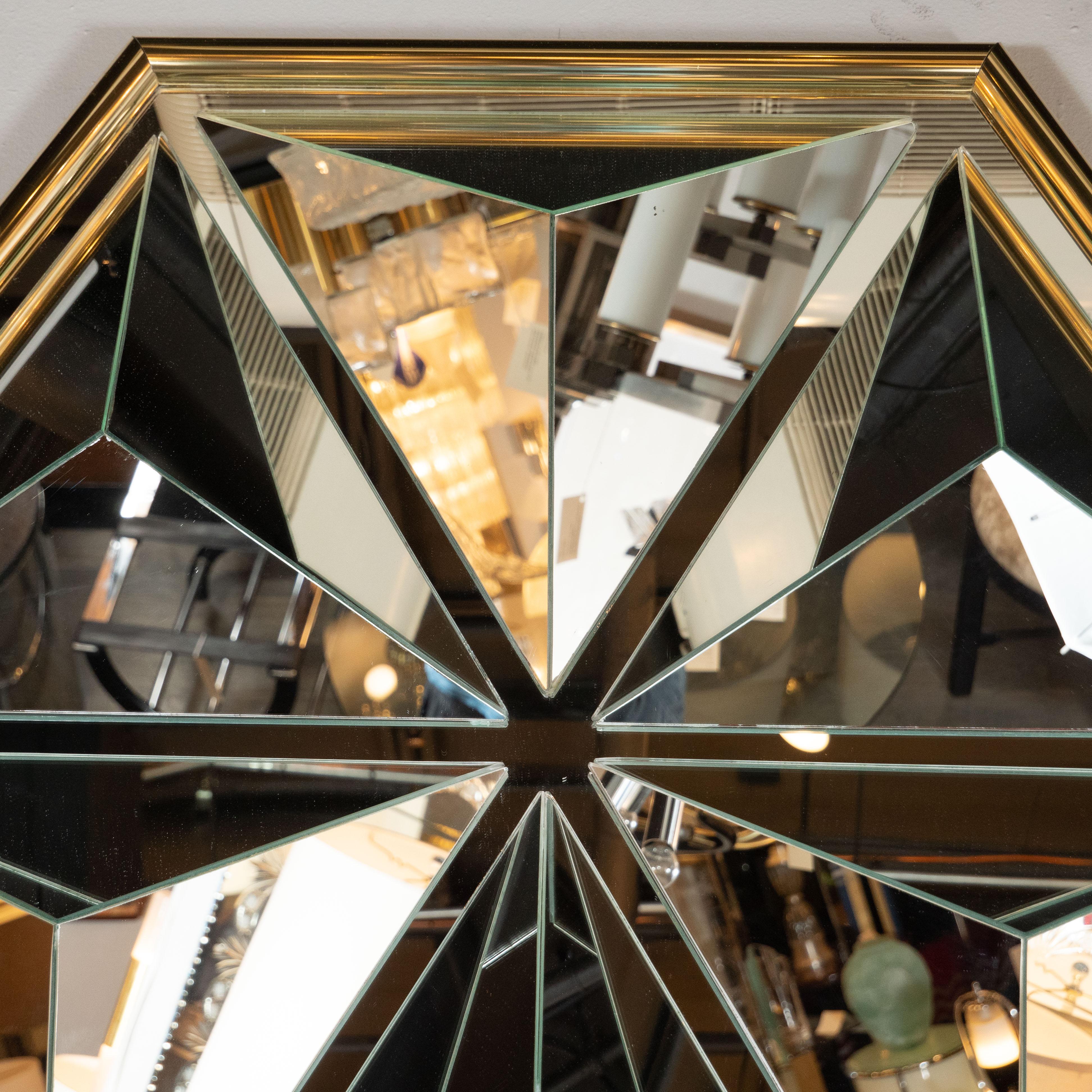 This graphic and sculptural Mid-Century Modern mirror was realized in the United States, circa 1970. It features a hexagonal form wrapped in brass. The body of the mirror offers six raised pyramidal forms, each composed of three individual triangles