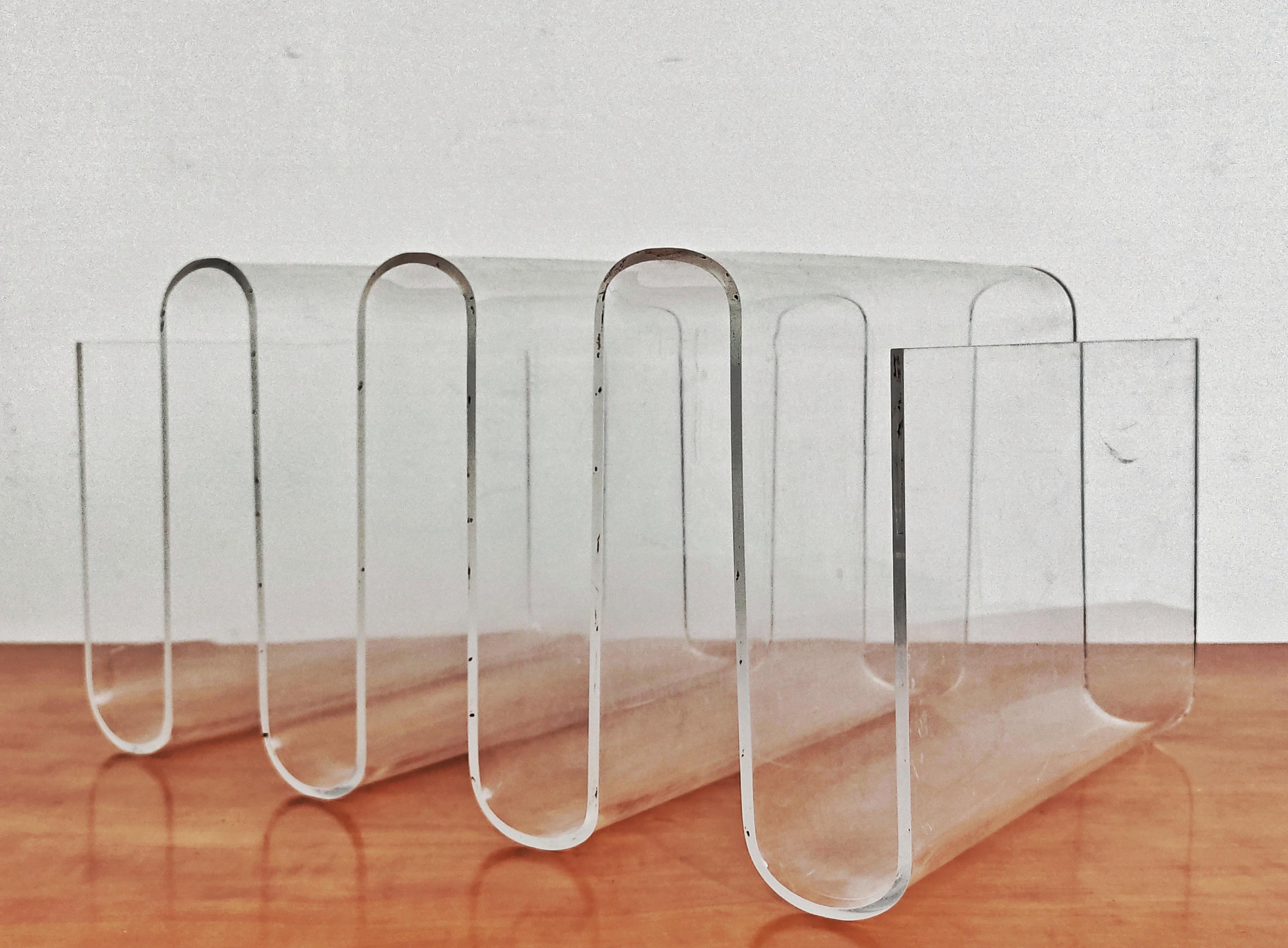 Dans cette annonce, vous trouverez un superbe porte-magazines de l'âge de l'espace. Elle est réalisée en plexiglas et présente un motif caractéristique de vagues en zigzag incurvées, typique de la fin de la période du milieu du siècle, communément