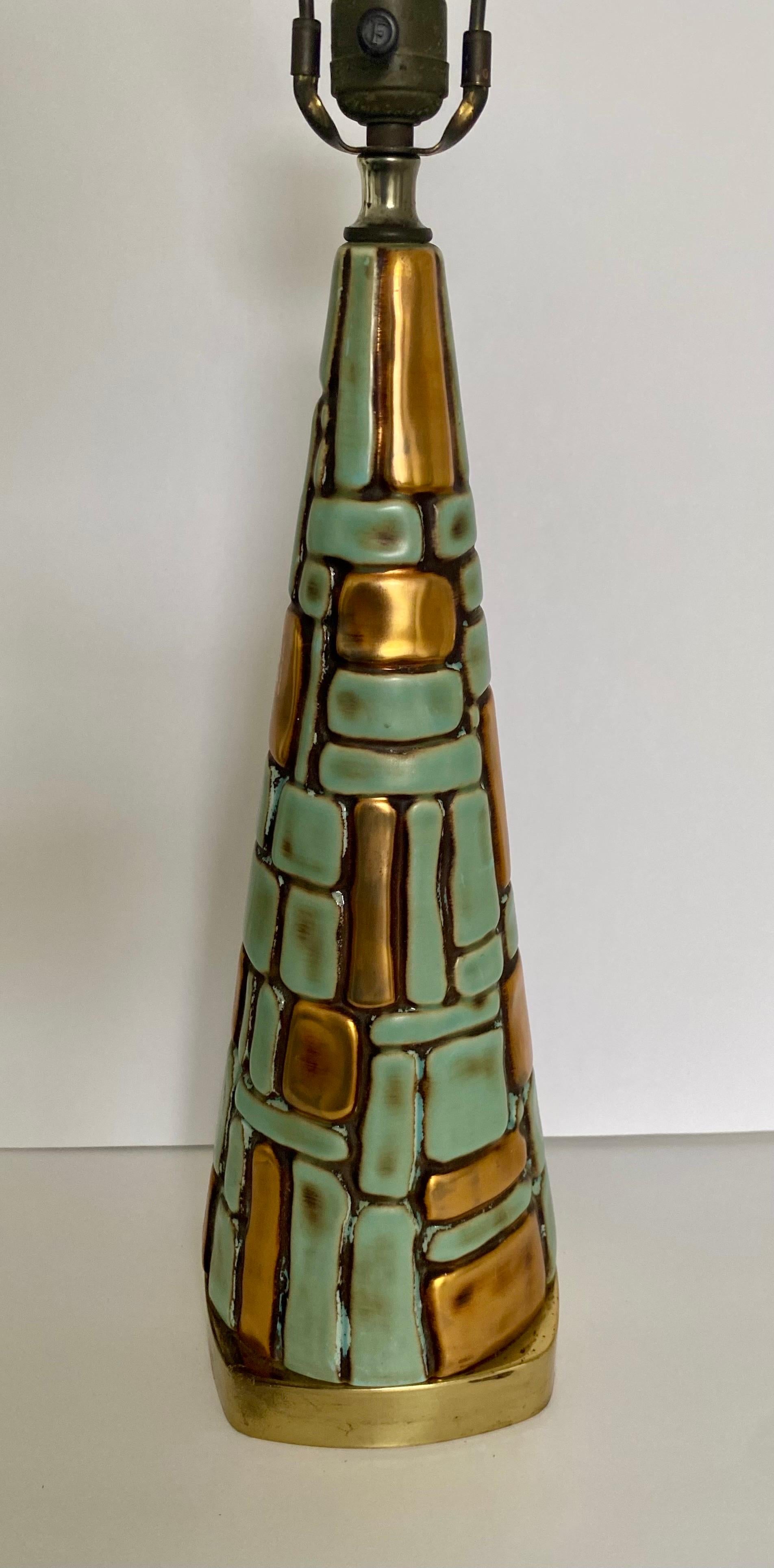 Fabulous Mid-Century Modern brutalist style table lamp. This sculptural pyramid form lamp features a textured stone-like raised mosaic design in vibrant turquoise and warm metallic gold painted tones. This eye-catching lamp is mounted on a square