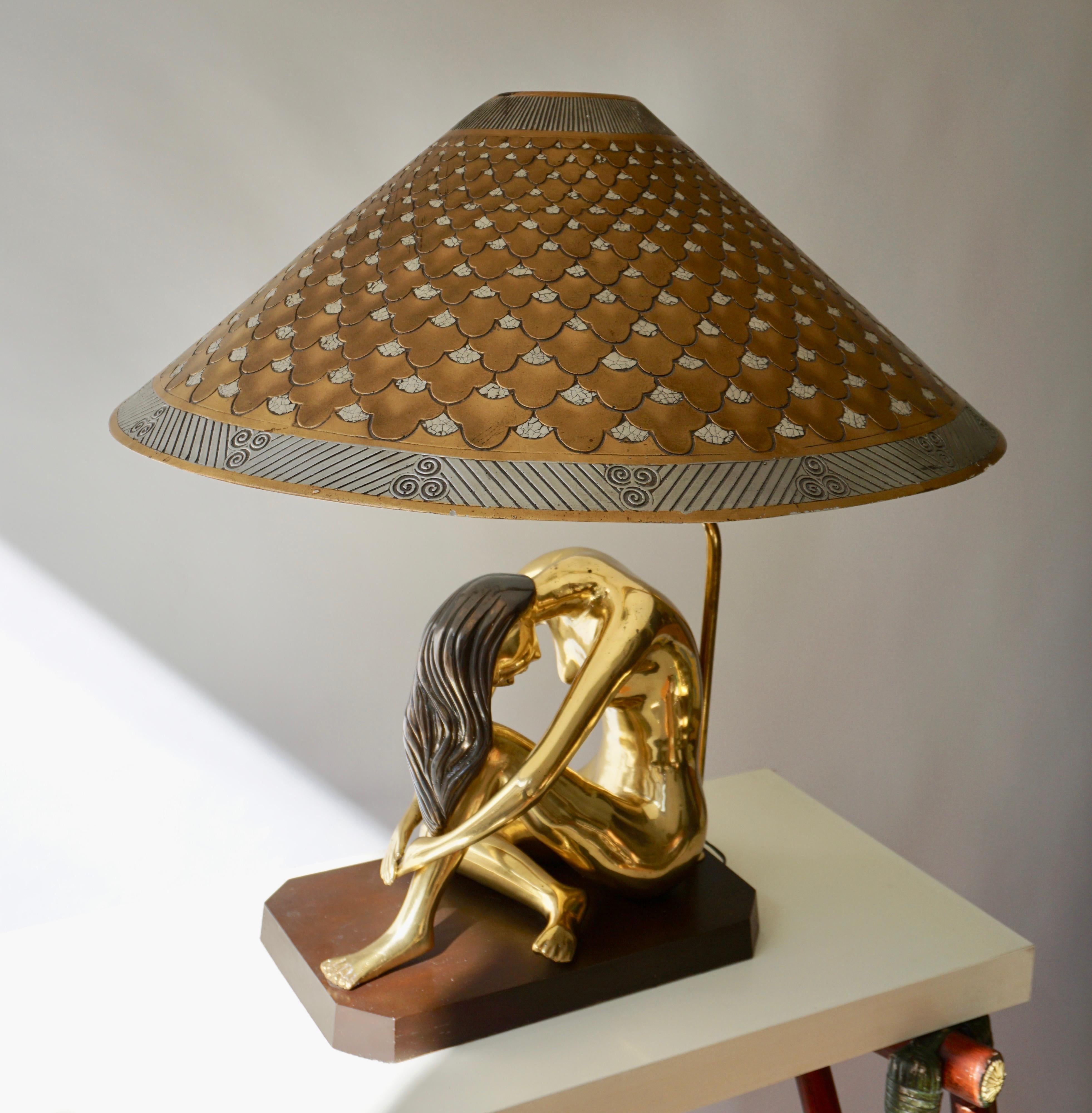 Sculptural table lamp of a bronze nude woman on a wooden base.
The lampshade is made of plaster and straw and is from the 1920s.
Measures: 
Height with shade 72 cm.
Diameter shade 64 cm.
Base 38 cm - 22 cm.