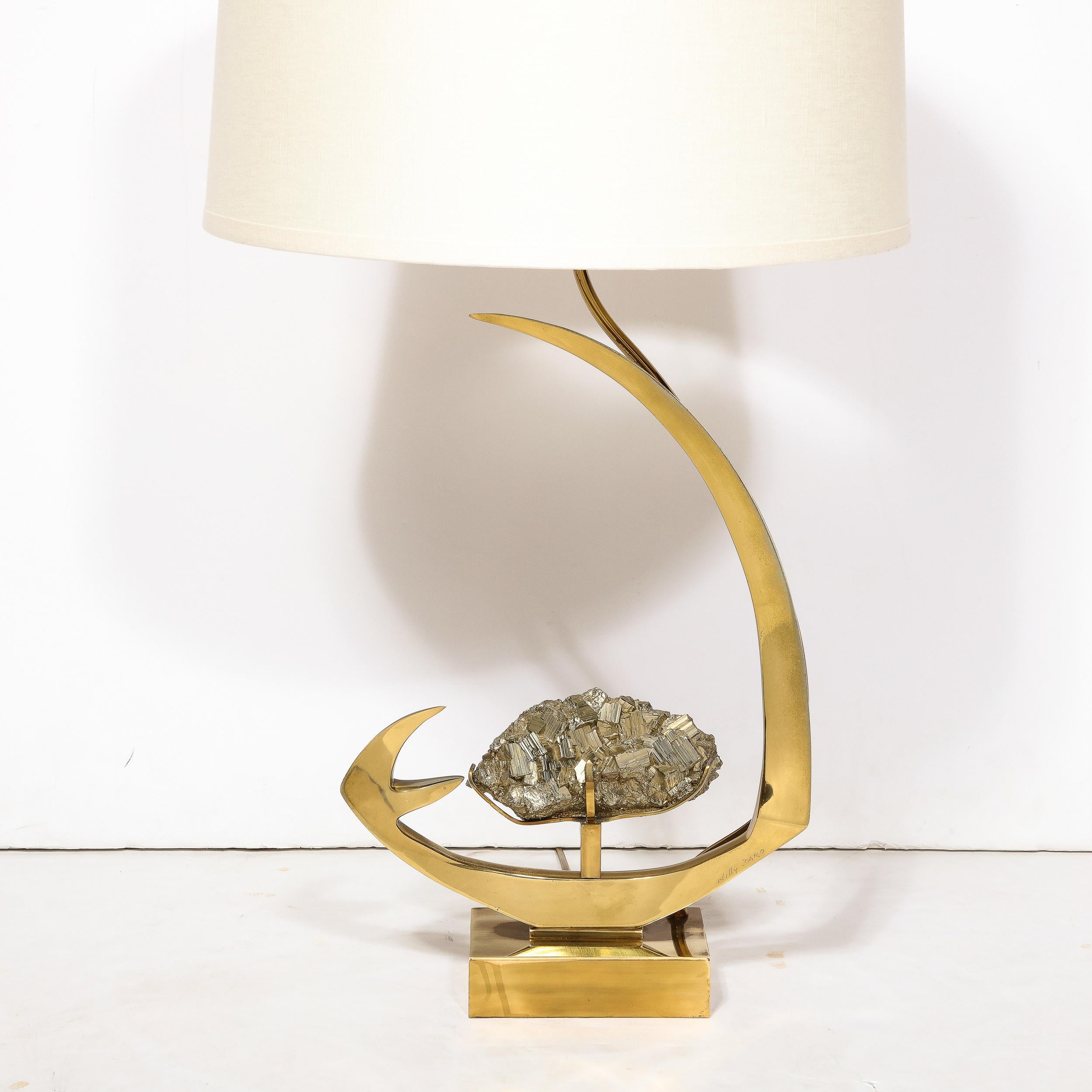 This striking table lamp is truly a gem of Mid-Century Modernist design paired with stunningly sharp and precise execution and lovely materials, created by the Artist Willy Daro in Belgium Circa 1970. Featuring a stylized angular swoop in polished