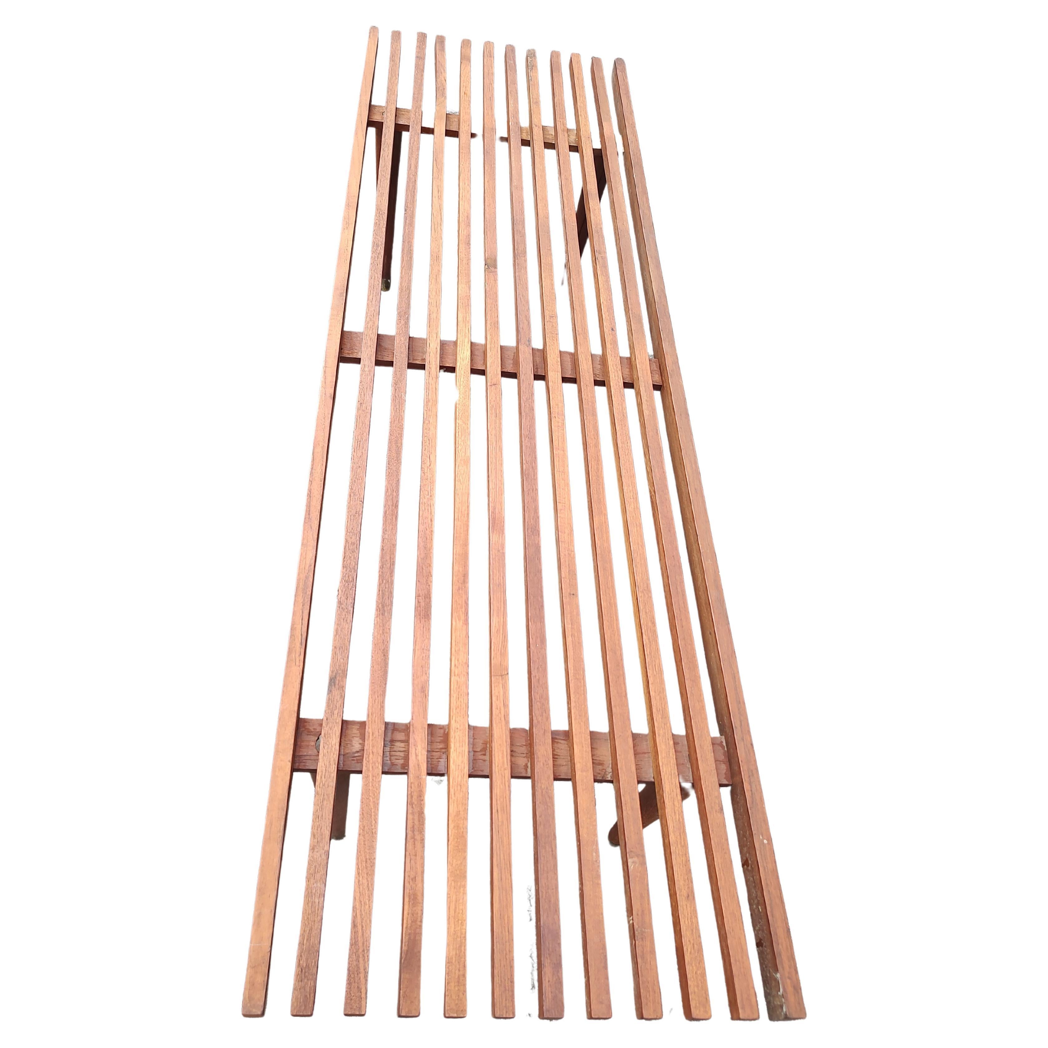 Fantástica mesa de cóctel de listones de madera de teca al estilo del icónico diseño de George Nelsons. Raro de encontrar en Teka. Patas torneadas con sabots de latón. En excelente estado vintage con un desgaste mínimo. Las patas se desenroscan para