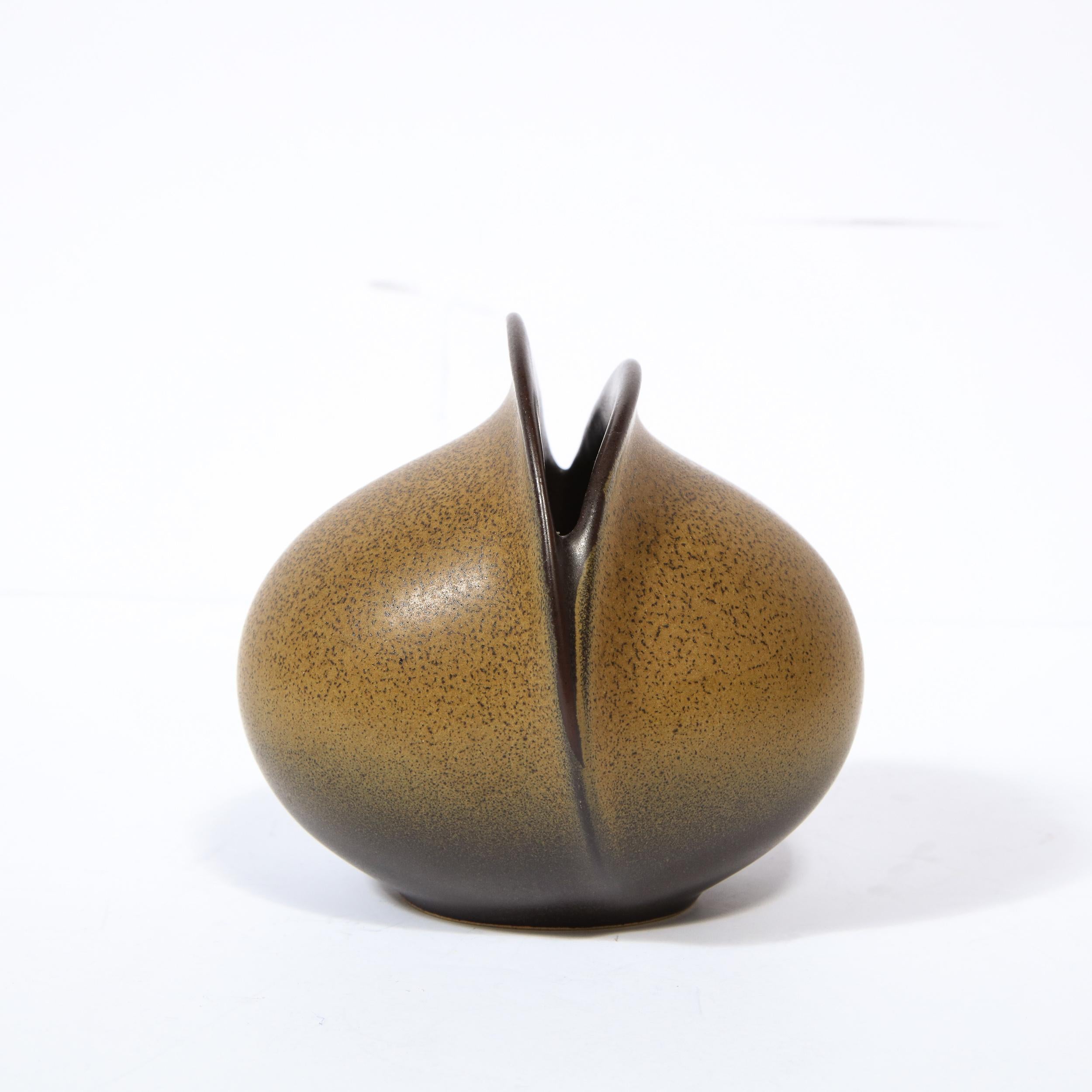This refined and sculptural vase was designed in Germany by the esteemed maker Rosenthal circa 1960. It offers a spherical form with an ovoid slit. The exterior of the piece is tawny with umber detailing. The interior of the piece is also painted in