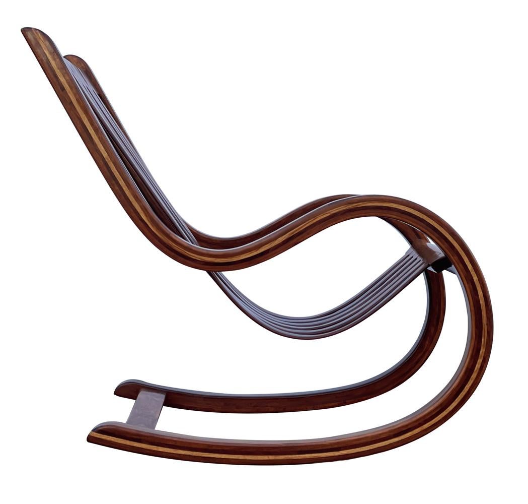 This studio made rocking chair is a stunning work of art. It features laminated exotic hardwood construction in a breathtaking sculptural form. In well cared for condition.