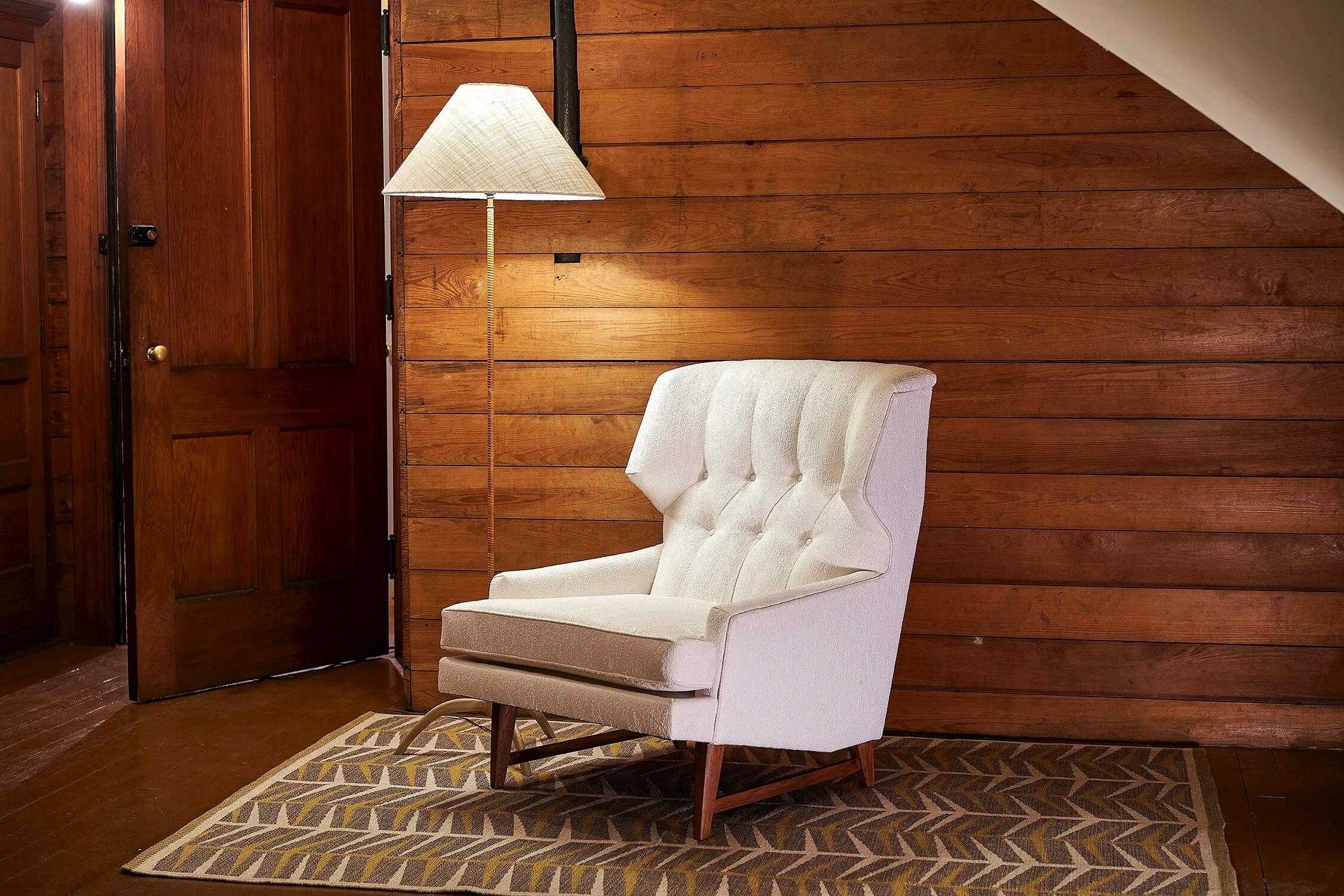 Außergewöhnlicher Mid Century Ohrensessel im Stil von Edward Wormley für Dunbar
USA ca. 1960er Jahre

Herrschaftliches Design mit beeindruckenden Linien und tief getufteten Kanälen, neu gepolstert mit weißem Bouclé
Auf kantigem Sockel mit