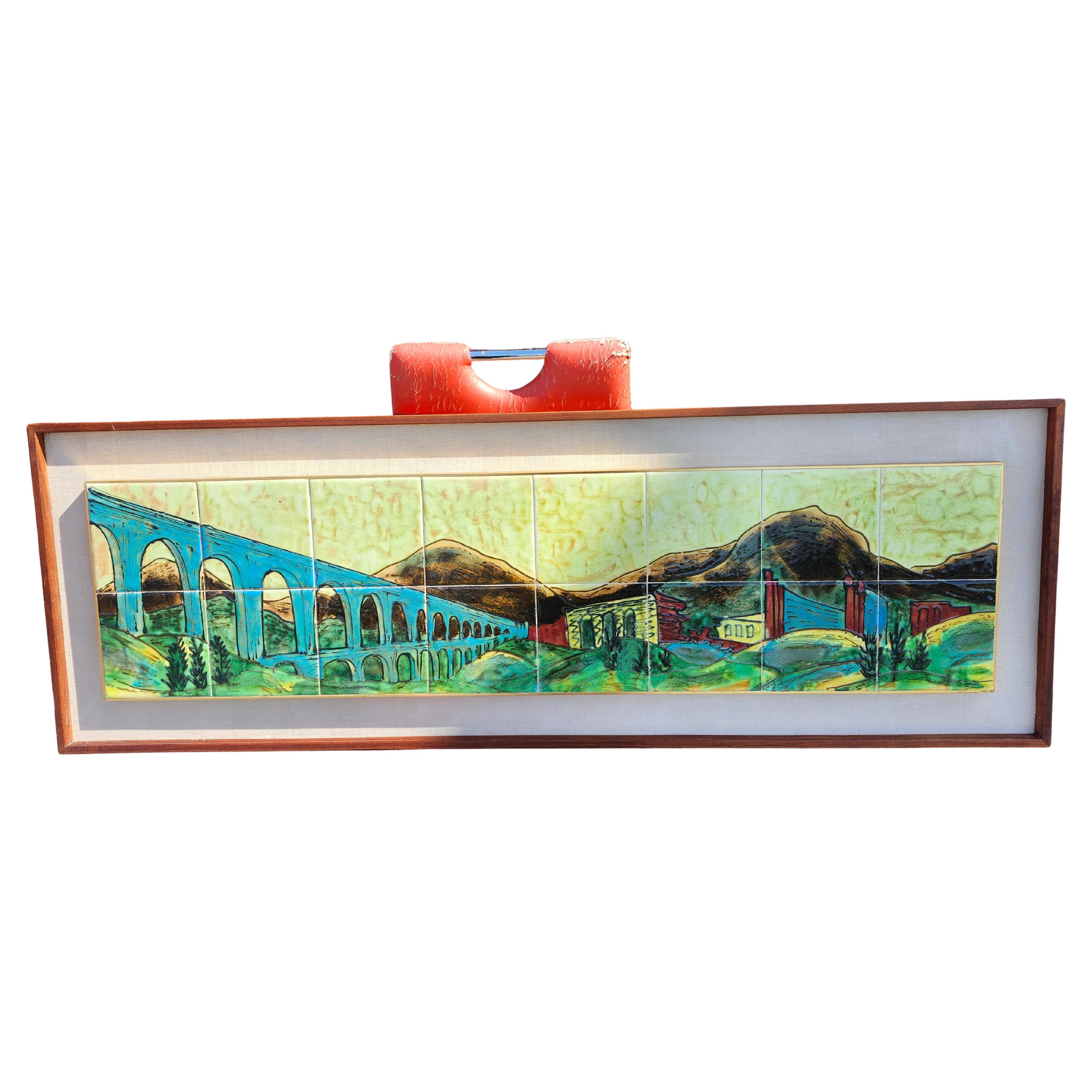 Fabuleux grand carreau représentant un paysage romain comprenant un aqueduc et d'autres bâtiments. Colorée et réalisée avec goût sur 18 carreaux carrés qui sont ensuite encadrés dans un cadre en noyer d'époque des années 60 et un passe-partout en