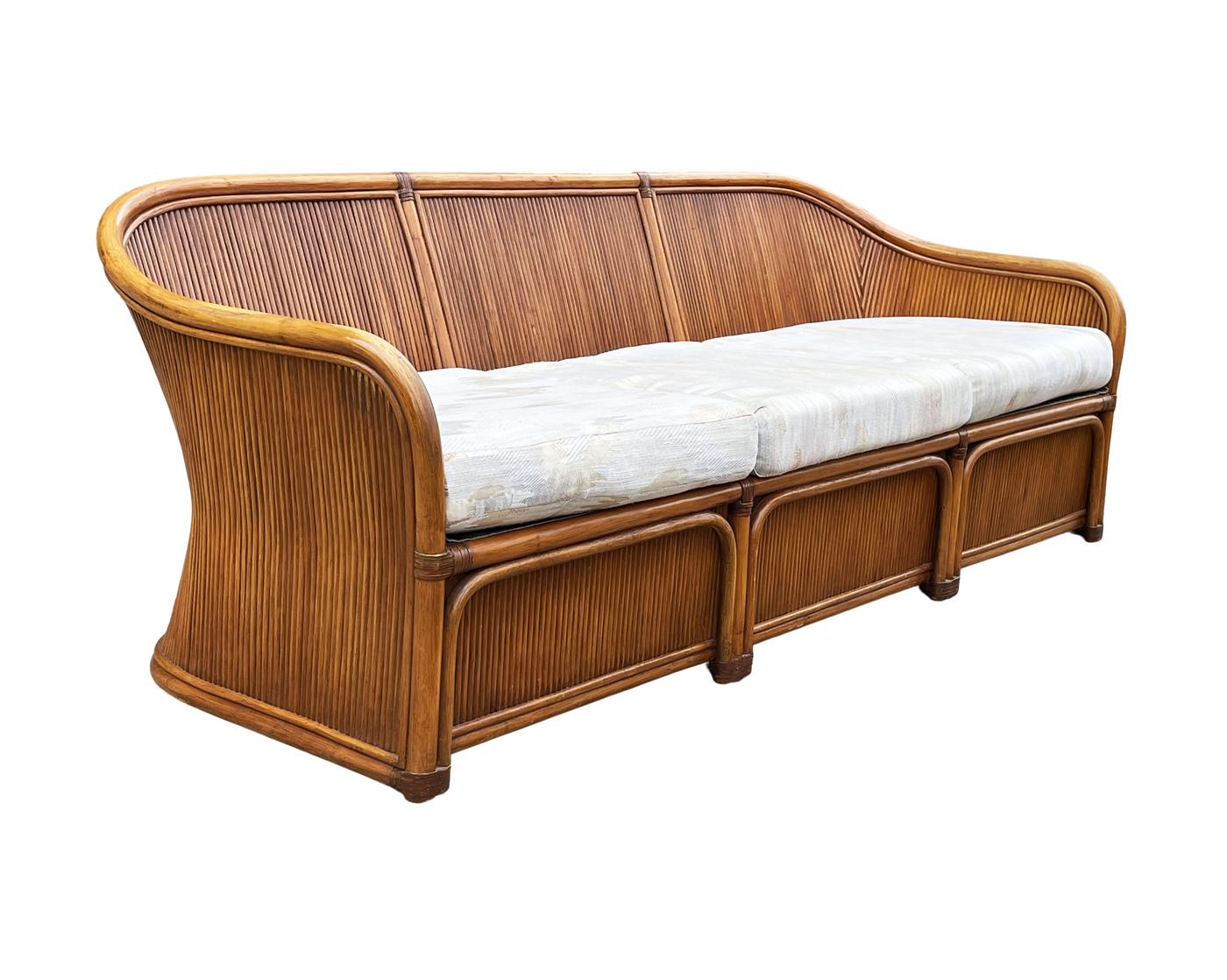 A stunning and well constructed bamboo reed sofa circa 1970's. This sofa features a sculptural design, dark stained bamboo construction, and its original cushions. Clean ready to use condition, cushions can use modern updating.
