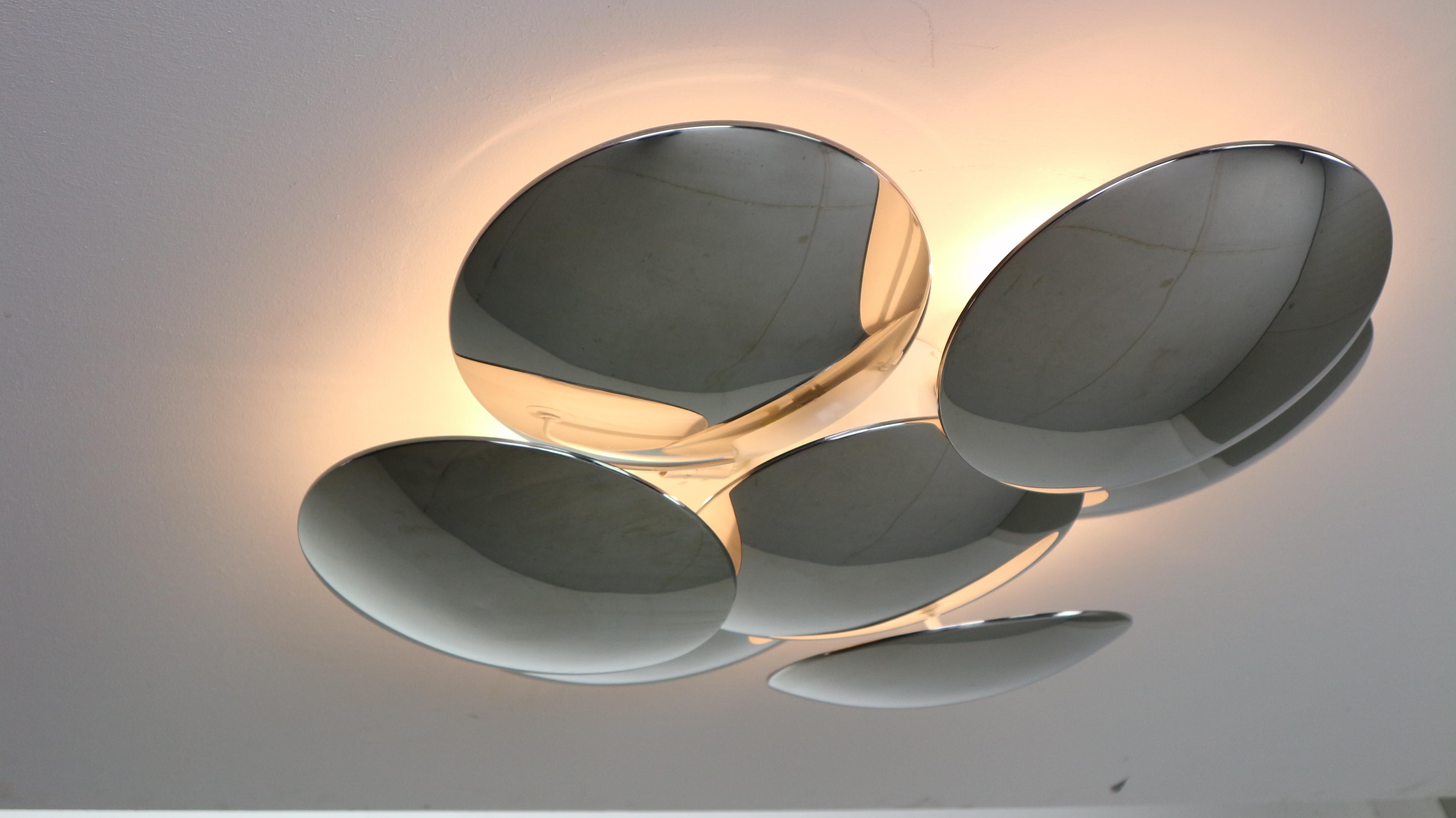 Mid-Century Modern period light fixture by Reggiani that can be either ceiling or wall mounted, made in 1970s period, Italy.
Composed of seven overlapping convex chrome disks that hide the white lacquered frame beneath. Holds three E26 sockets.