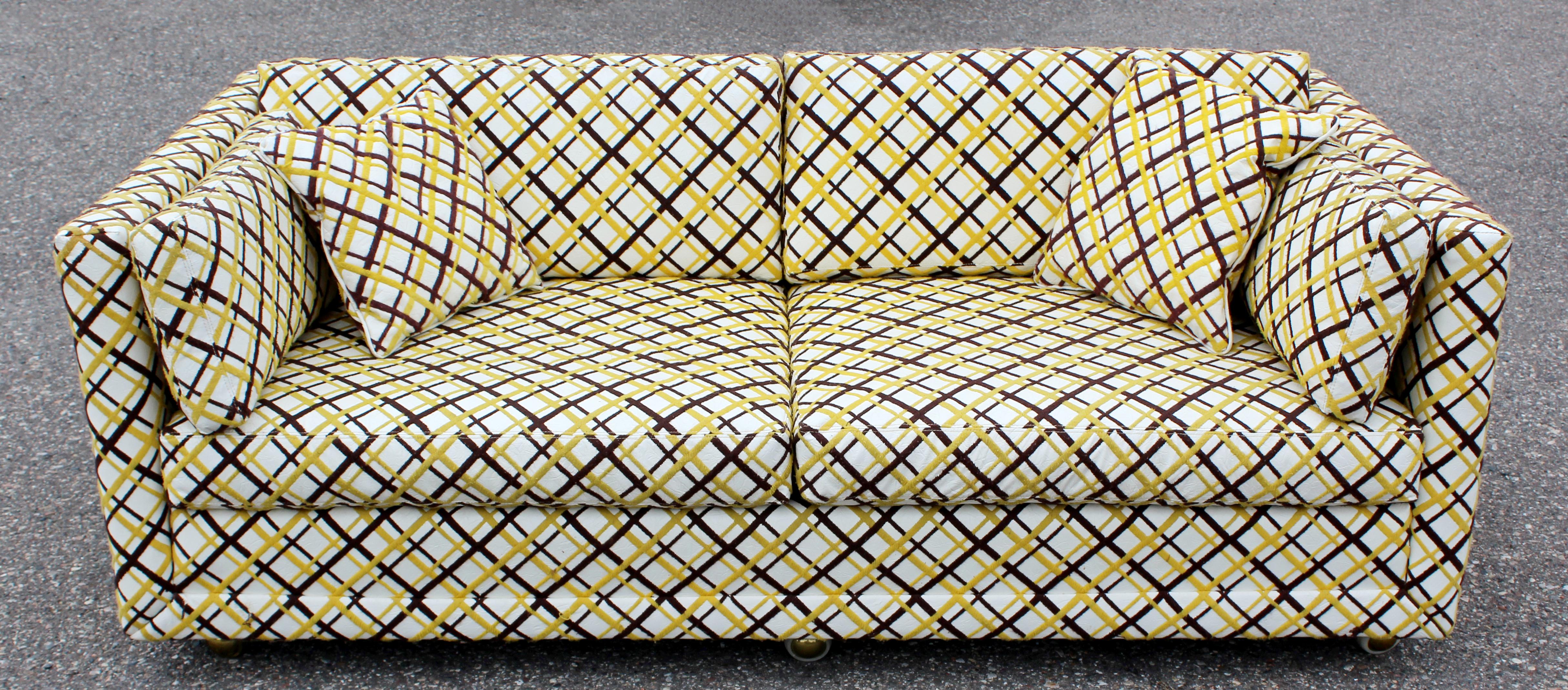 For your consideration is an extraordinary, large loveseat with front casters, upholstered in textured vinyl with a yellow top stitch, by Seemay Inc, in the style of Milo Baughman, circa 1970s. In very good vintage condition. The dimensions are 70