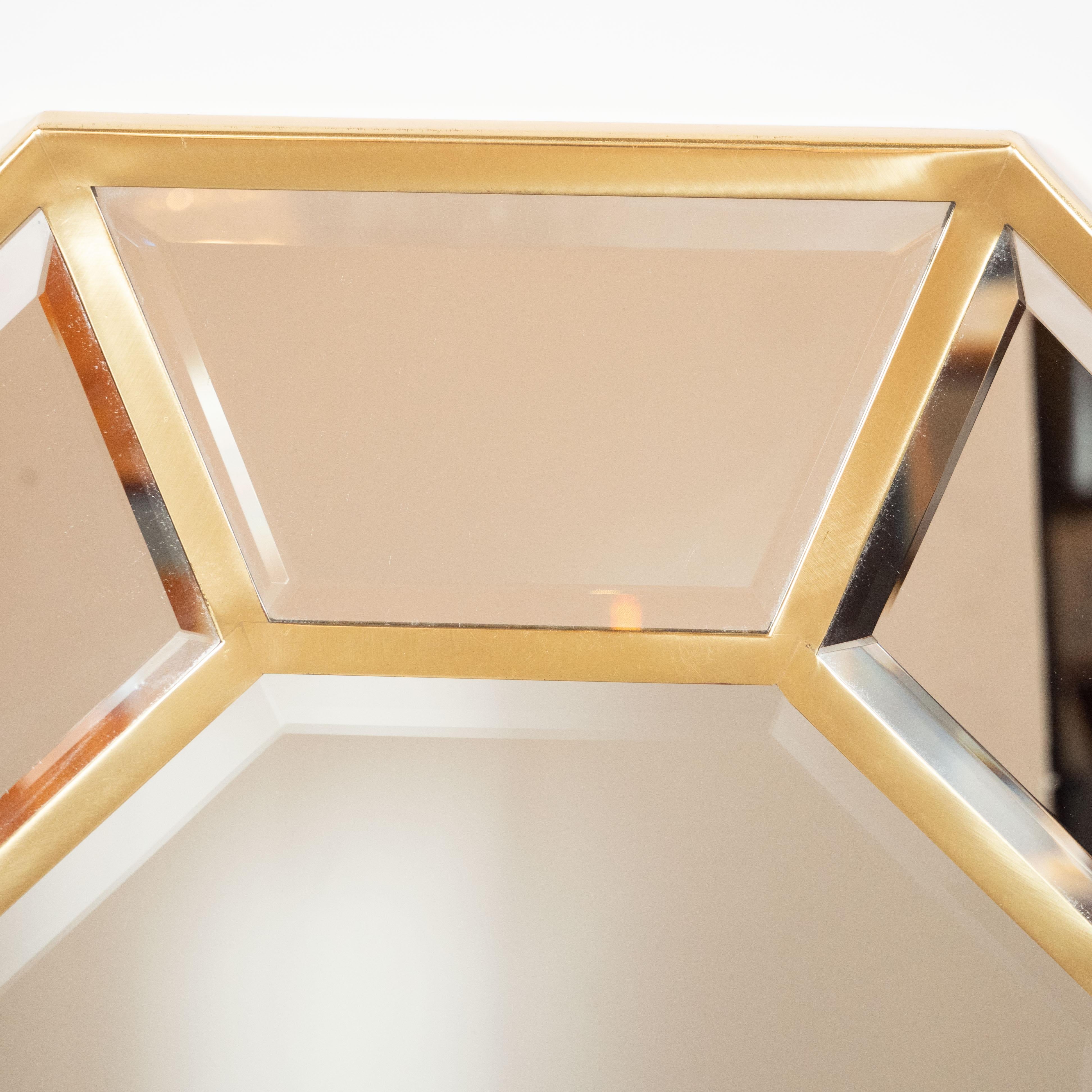 This refined mirror was realized in the United States, circa 1970. It features an octagonal silhouette- a form that is reiterated in the central mirrored panel surrounded by eight pentagonal inserts all framed in polished brass. With its clean