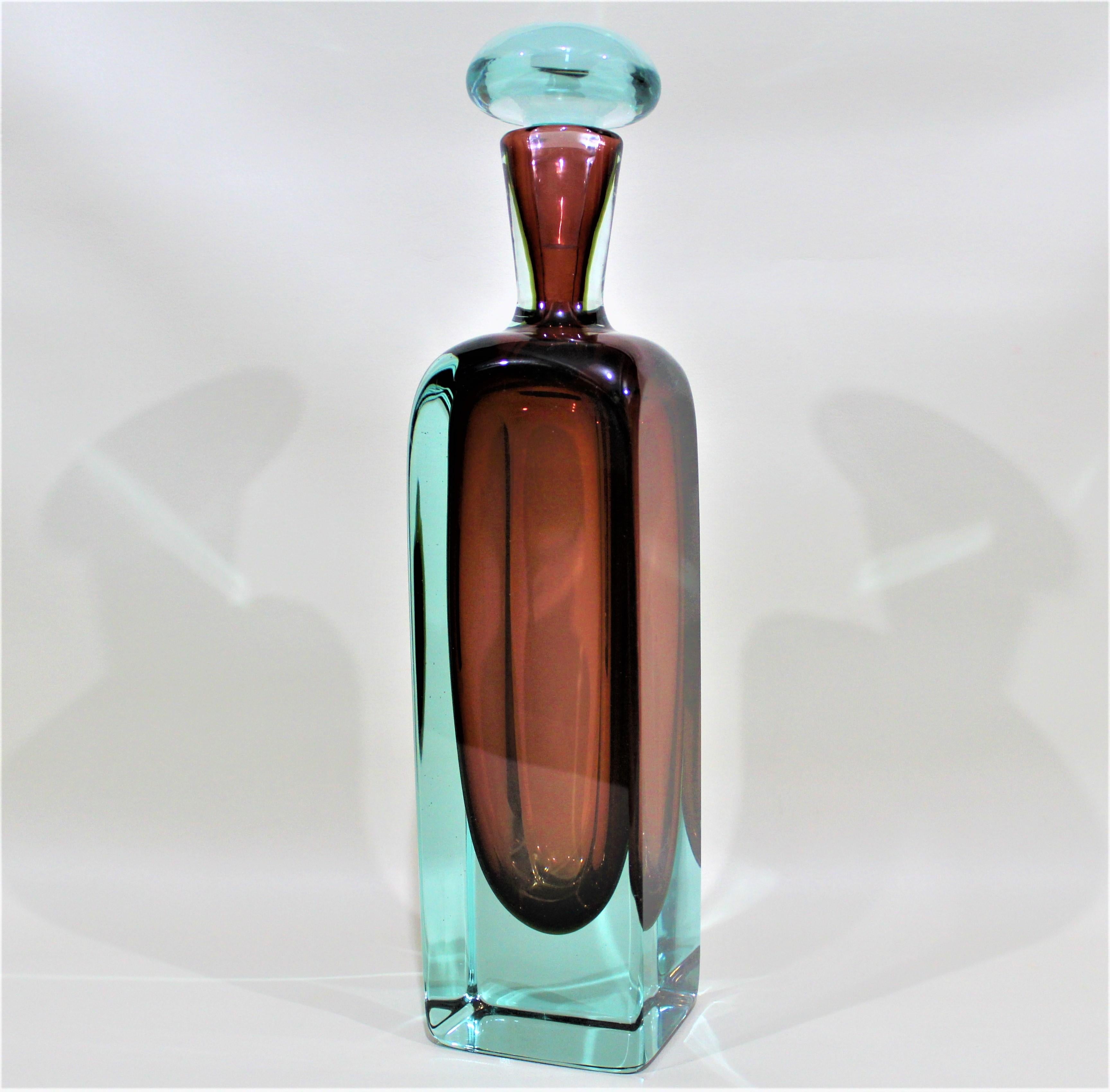 This heavy art glass bottle is unsigned and not labeled, but consistent with the style of the Italian Murano artist Angelo Seguso. This substantial art glass bottle is done in a thick ice blue outer layer which encases and compliments the deep red