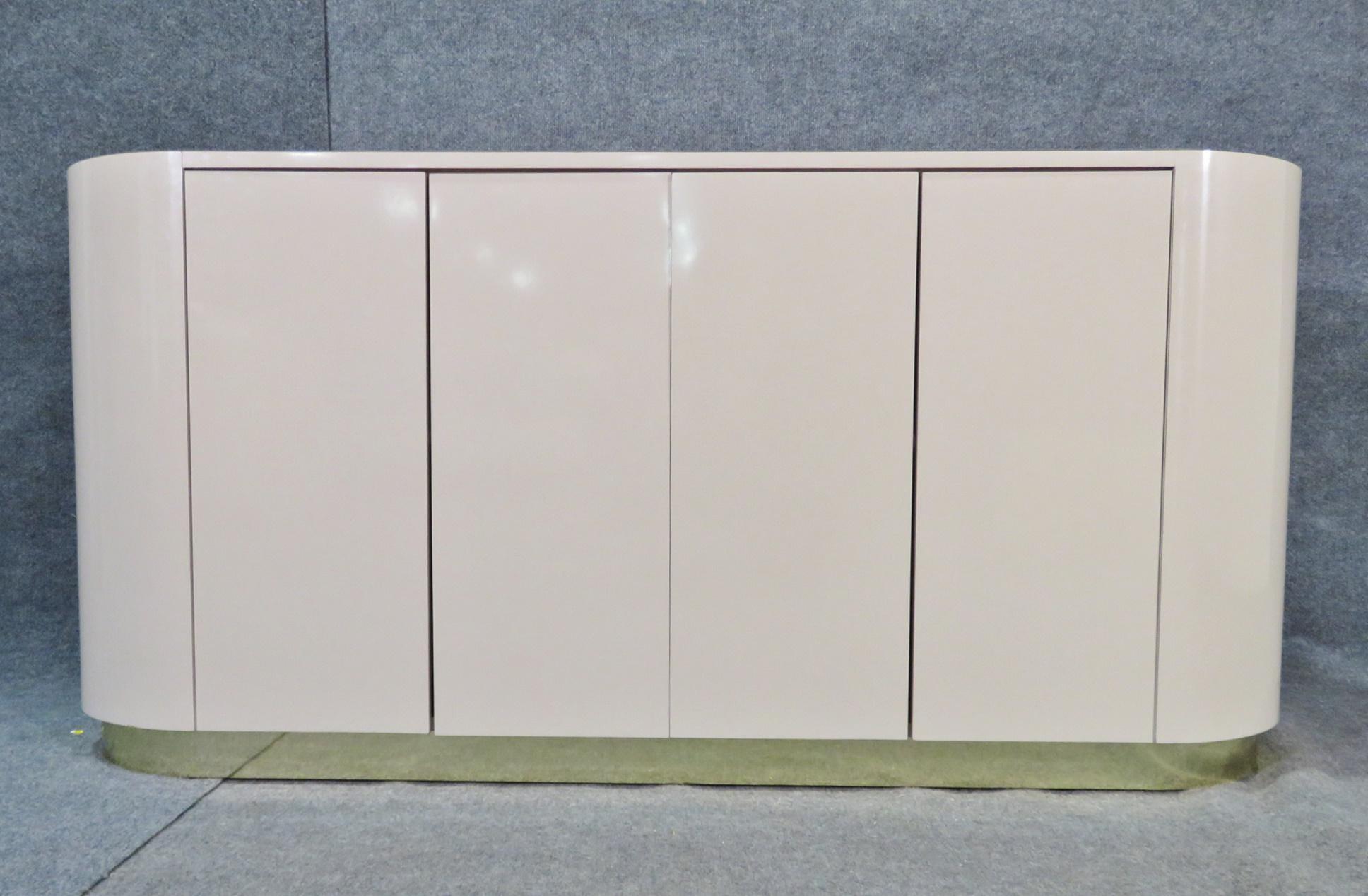 A beautiful Mid-Century Modern server with a smooth surface and minimal design, this piece styled after the work of Karl Springer is impressive and functional. Four doors open to reveal shelves and storage within. Please confirm item location with