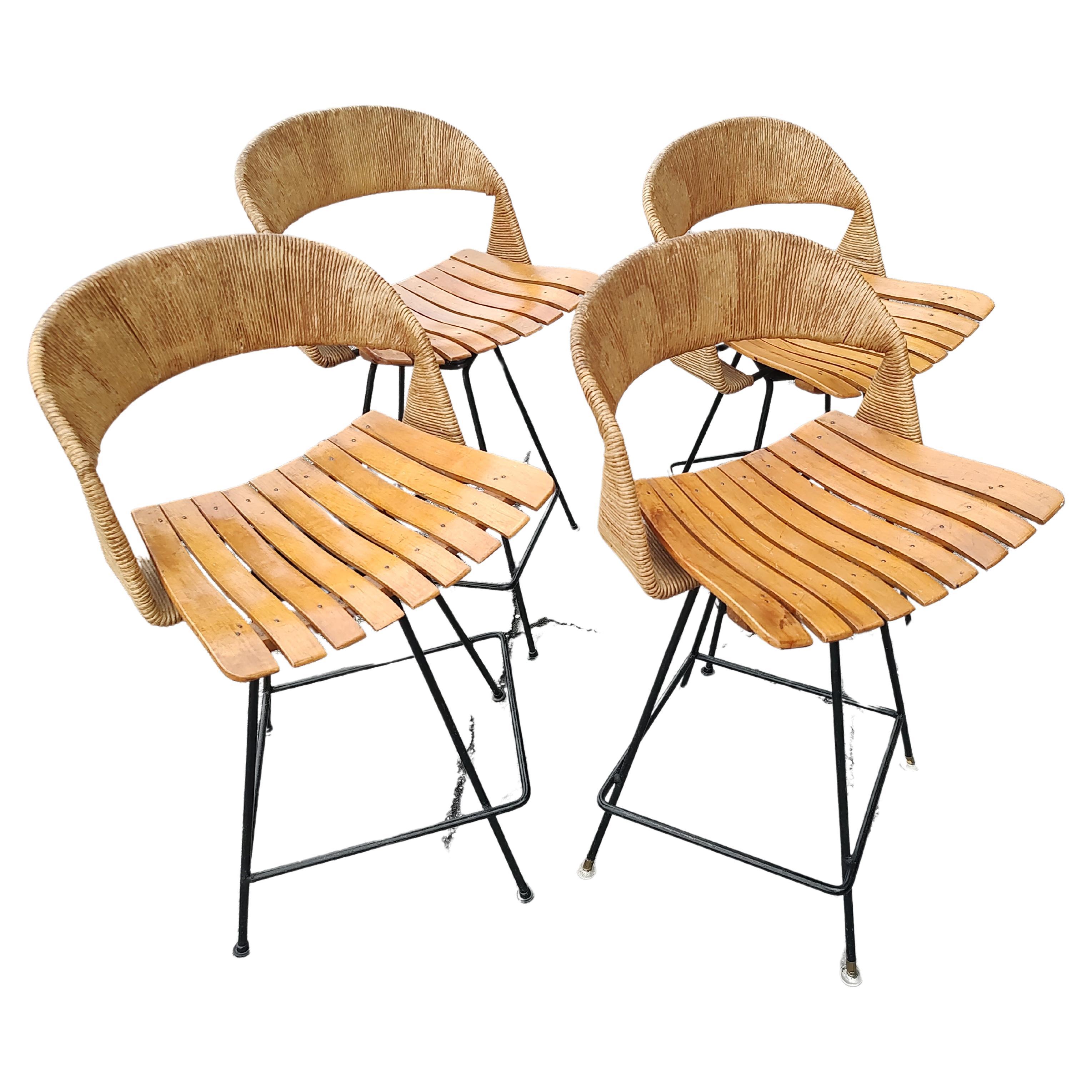 Fabulous pairs of bar/ counter stools by Arthur Umanoff for the Boyeur Scott furniture Co. C1960. Sold as pairs for you're convenience as you can buy all 4 also. 
Construction is an iron frame with a Swiveling seat of maple and a paper cord, raffia