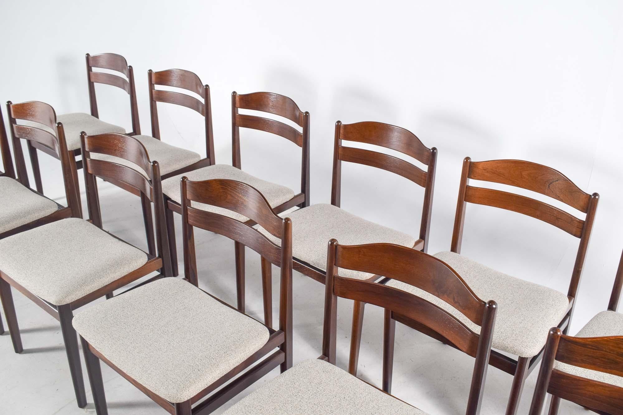 Dieses exquisite Set aus 12 Esszimmerstühlen von B.S. Møbler verkörpert die zeitlose Eleganz des Designs aus der Mitte des Jahrhunderts. Diese Stühle aus warmem, reichem Palisanderholz weisen die für diese Epoche charakteristischen klaren Linien und