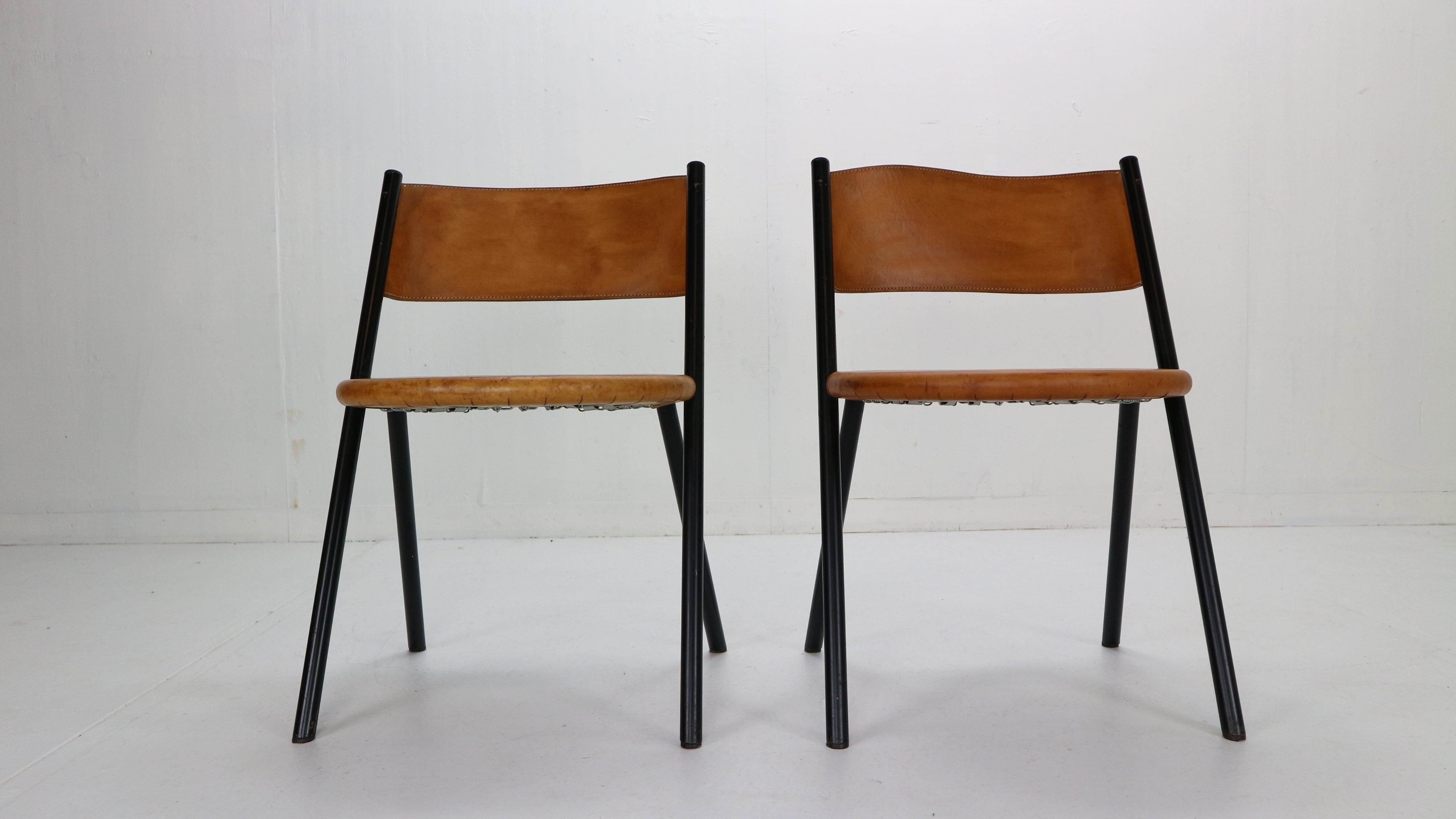 Mid-Century Modern period very rare Italian design chairs manufactured in 1970s, Italy.
Set of 2 chairs consists original thick cognac leather seatings and curved backrest attached on a minimalistic black metal frame.
Due to its age leather