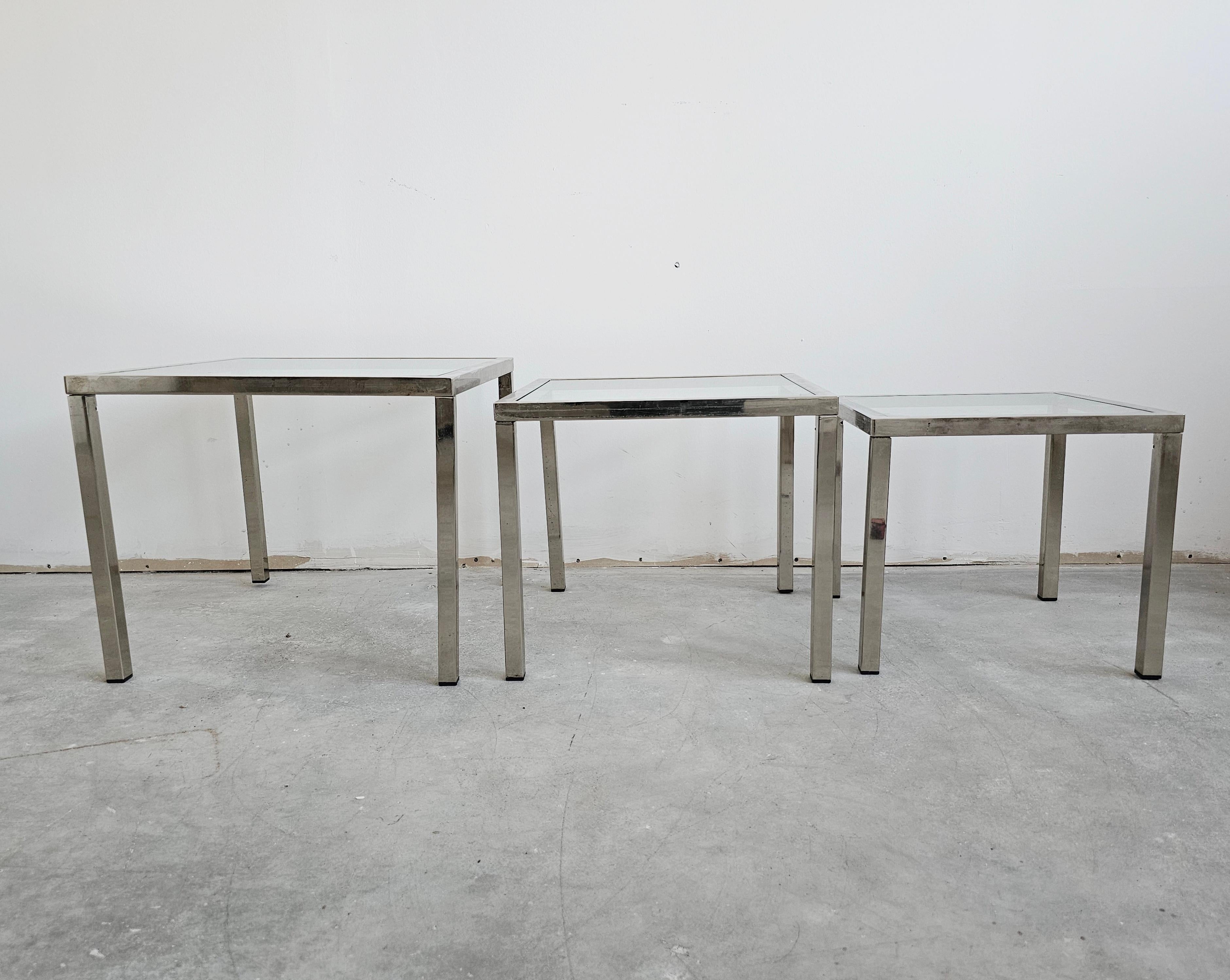 Cette liste comprend un ensemble vintage de 3 belles formes carrées mid century moderne chrome et tables gigognes avec des dessus en verre. Parfait pour les petits appartements ou les coins de la maison. Leur design minimaliste les rend très